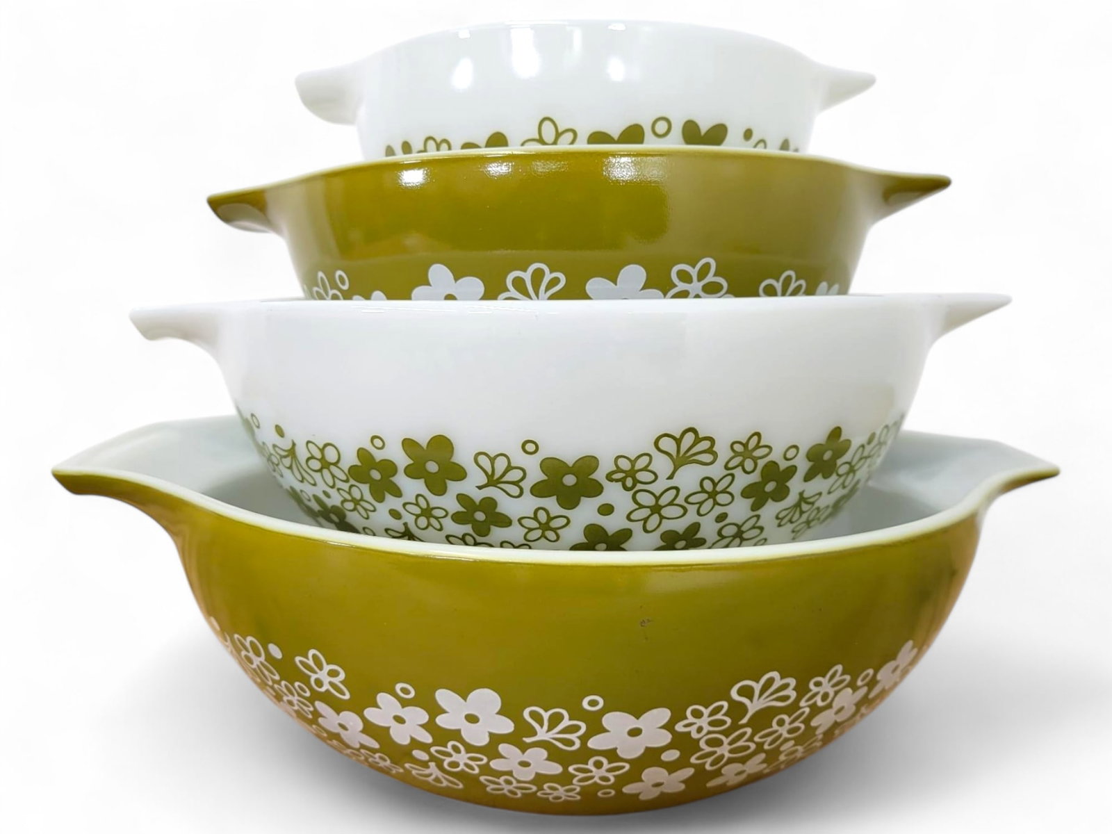 Pyrex Spring Blossom Mixing Bowl Set: A set of four vintage Pyrex Spring Blossom mixing bowls in alternating green and white with floral designs. Each bowl features signature handles for easy pouring and stacking. The set is in very good 