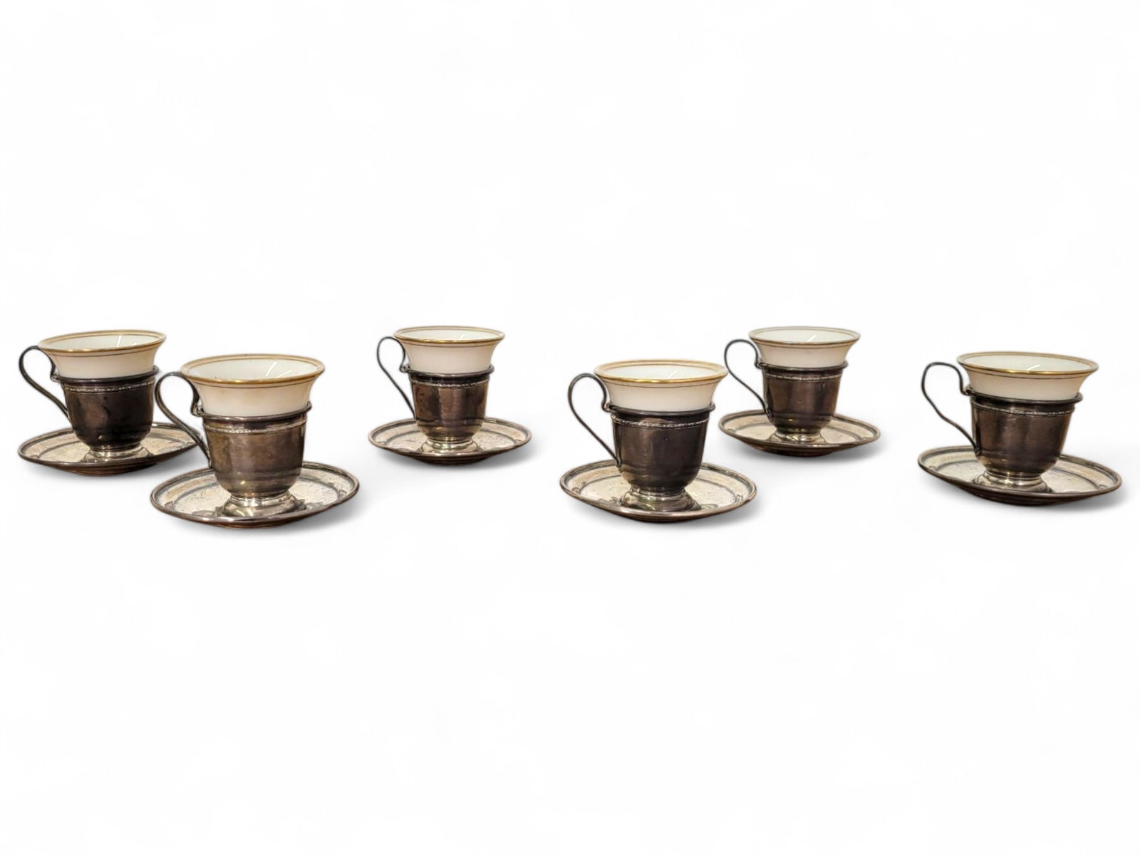 Set of Six Porcelain and Silver Demitasse Cups: This lot offers a set of six Belmonte porcelain demitasse cups with silver holders and matching saucers. The cups feature a simple design with a gold rim, and the silver holders add a touch of eleganc
