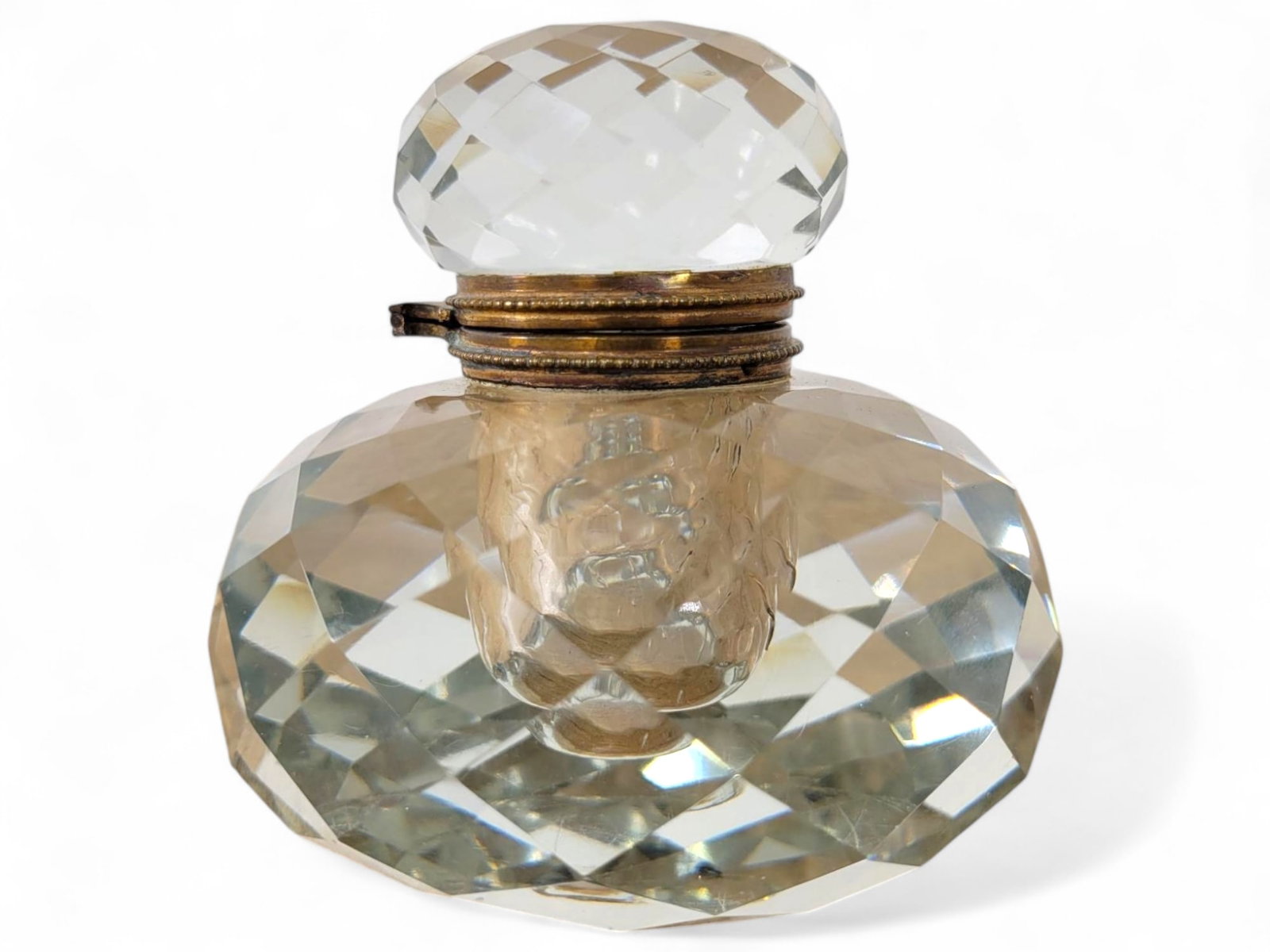 Antique Faceted Glass Inkwell with Matching Lid: A stunning faceted crystal inkwell with a matching crystal lid. The geometric precision of the design gives it a sparkling elegance. Brass detailing on the hinge has minor wear. See photos for conditi