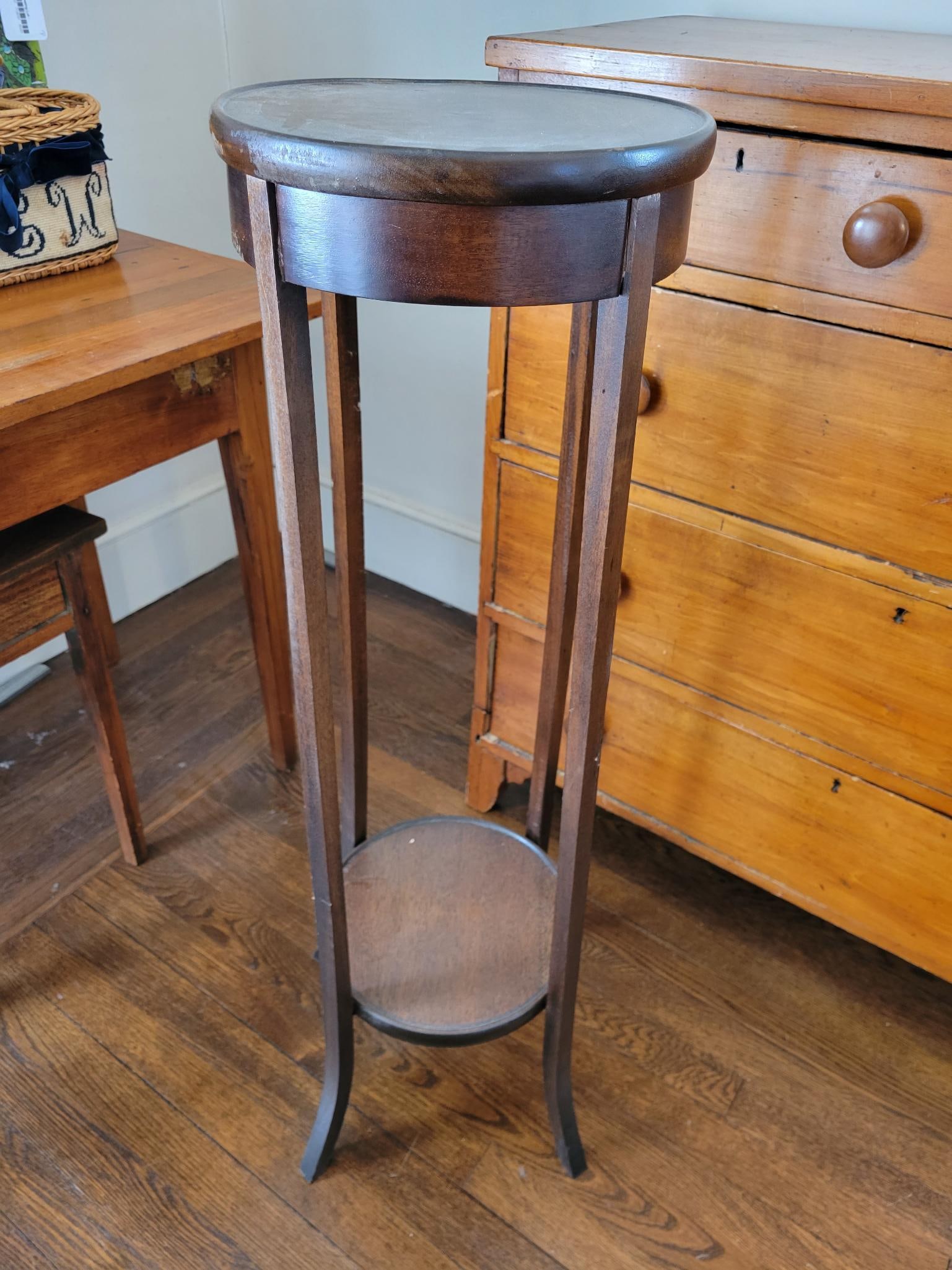 Antique Edwardian Wooden Pedestal / Plant Stand: This lot includes a Edwardian style early 20th century pedestal with 4 legs and a small shelf at the bottom. The piece is in good antique condition, one of the side skirt pieces needs to be regl