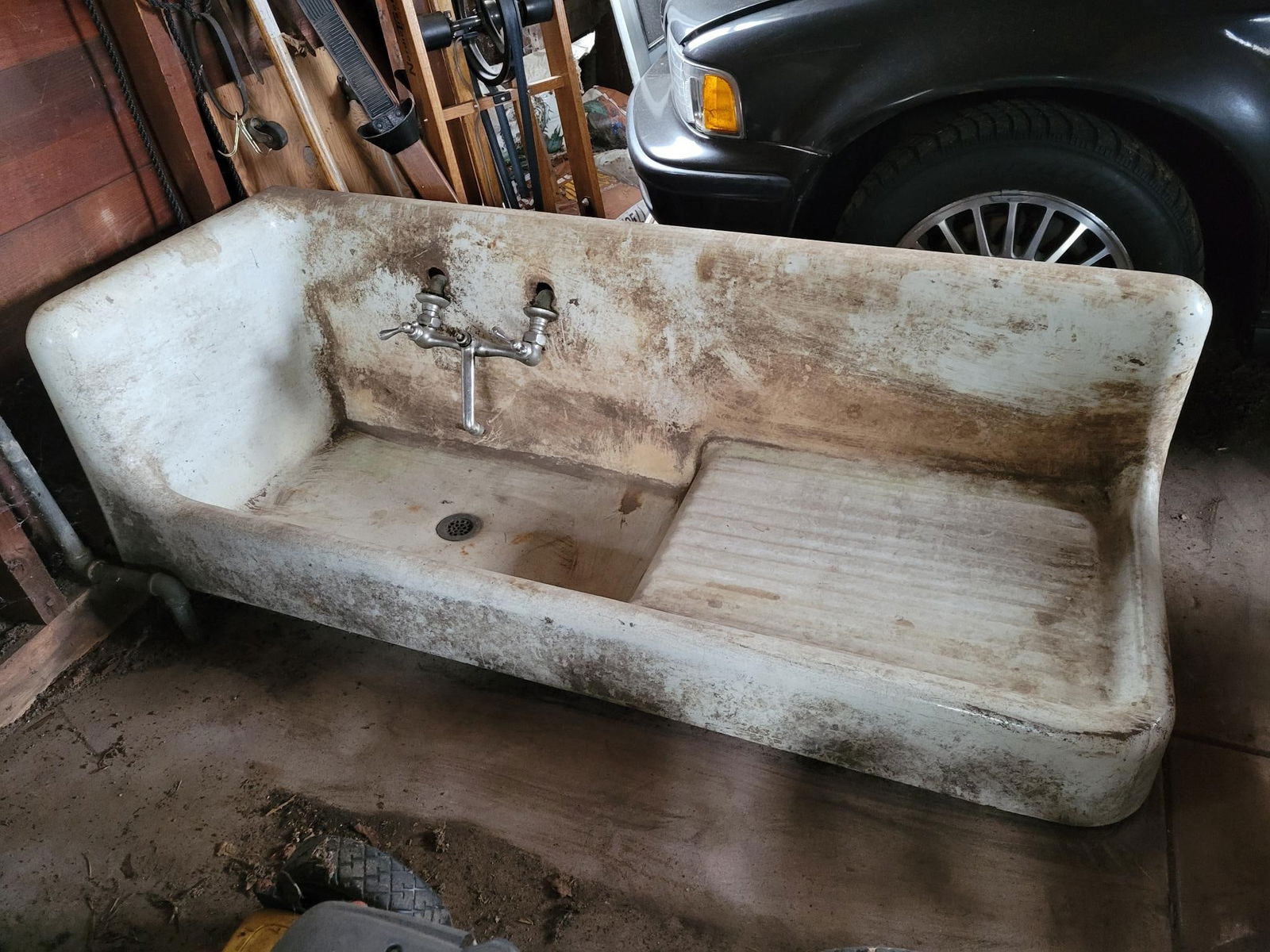 Large 60"L Porcelain Cast Iron Farmhouse Sink w/ Faucets: This lot includes a very large porcelain farmhouse sink, with the original faucets. The sink is in overall good antique condition, showing ware from age and use. It is very dirty from years of s