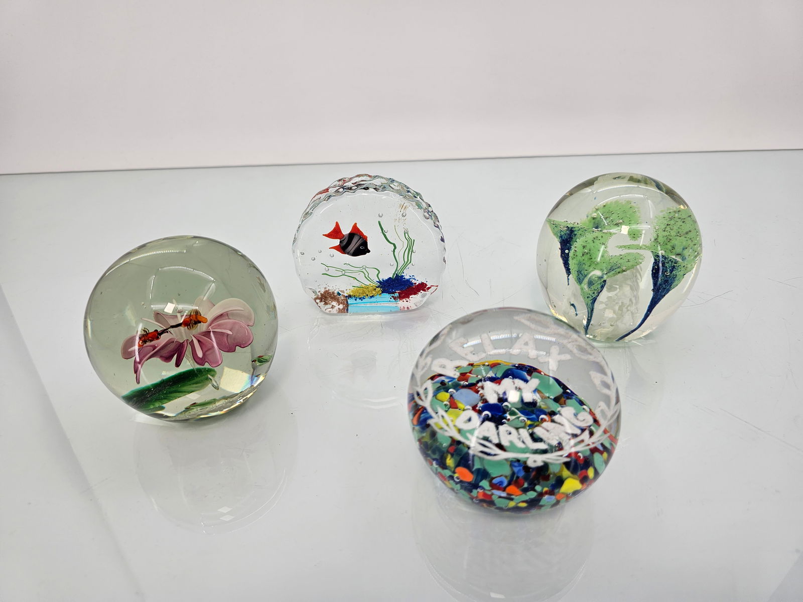 4pc Lot Blown Glass Paperweights - Fishbowls & Flowers: The set of paperweights are in good overall condition, included is a fishbowl, 2 with flowers, and a unique paperweight that reads "Relax my Darling" (Marked on bottom - See Photos). Each is in good o
