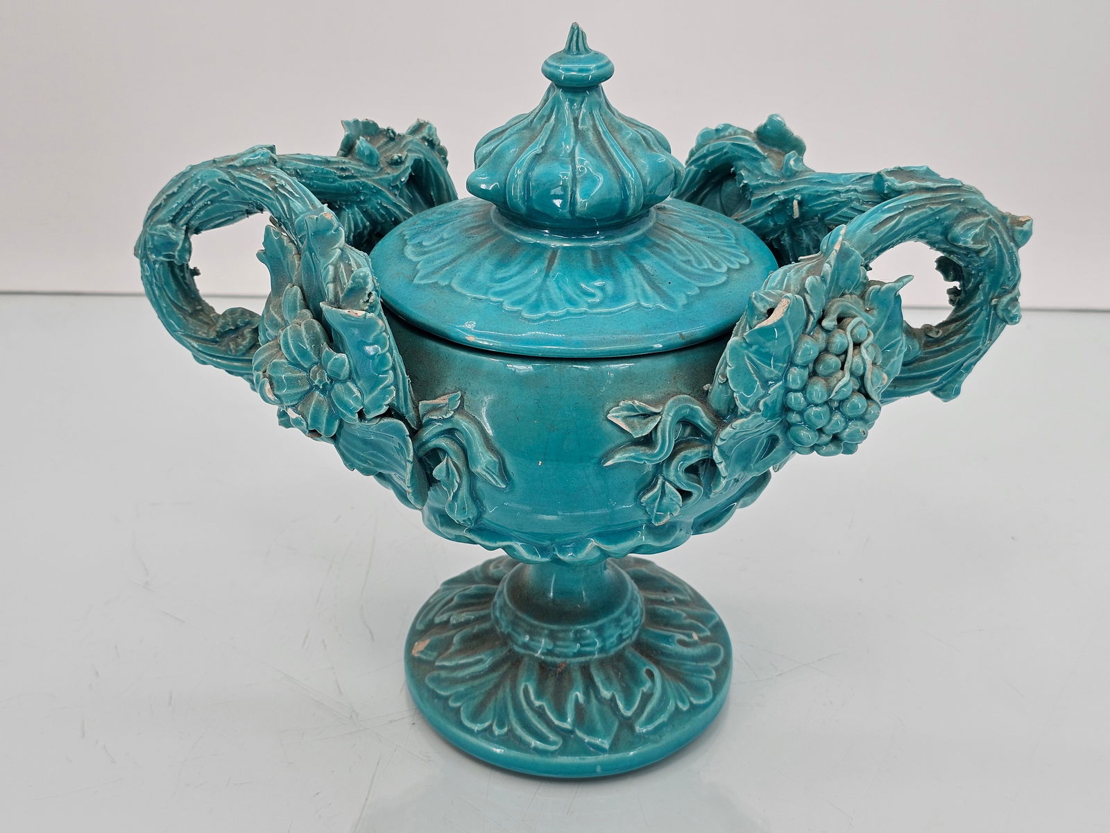 Antique Turquoise Blue Glazed Majolica Centerpiece Urn: The wonderful urn shows a bright blue glaze and details throughout. Appearing antique in age, the piece shows some losses and small chips here and there. See lot photos for more information on the lot