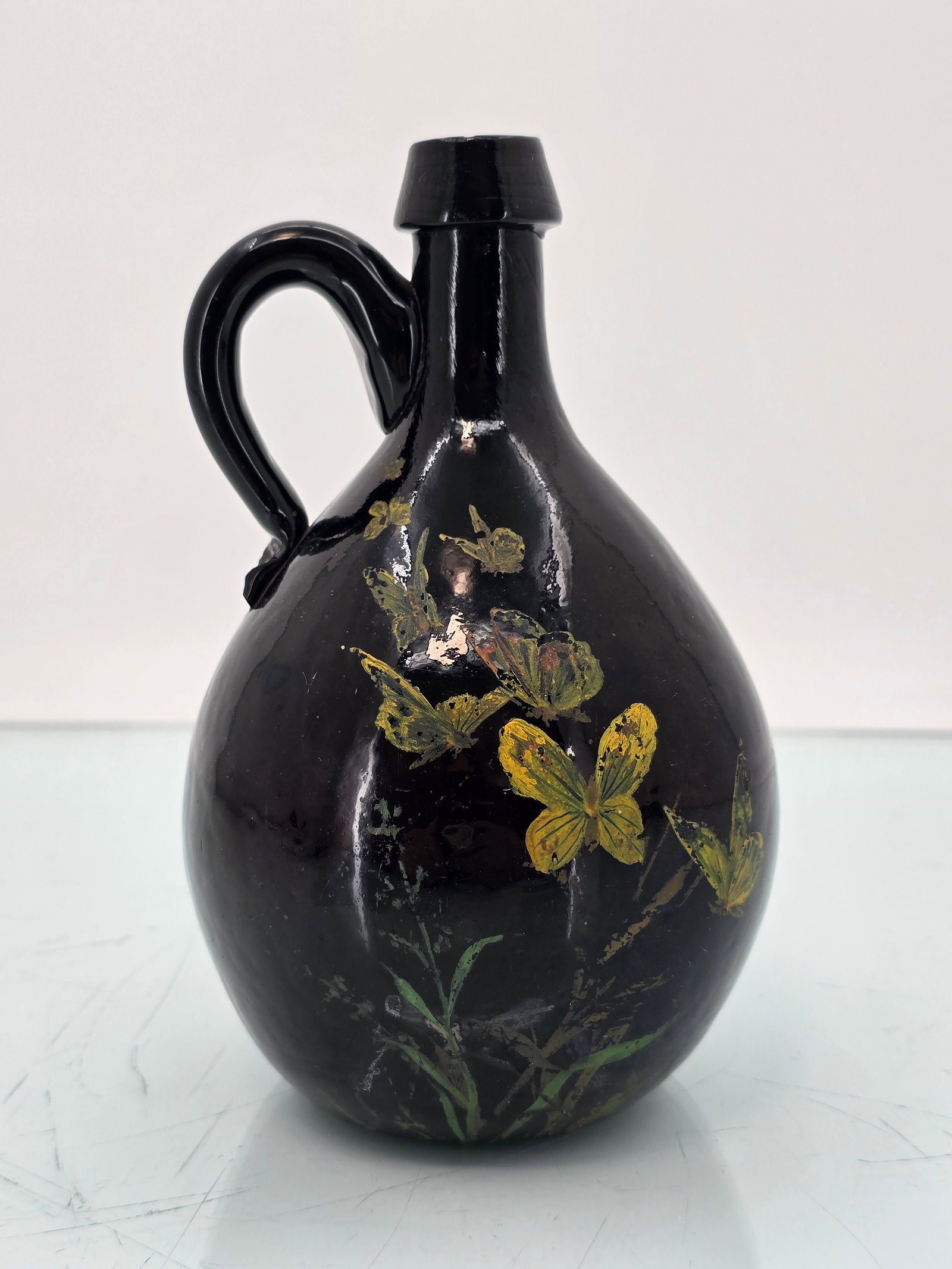 Handled Small Slope Shouldered Globular Whiskey / Liquor Jug Bottle: The handled, small slope-shouldered globular whiskey/liquor jug bottle is in overall good antique condition, showing typical signs of age and use. There are some small, shallow rough flakes at the bas