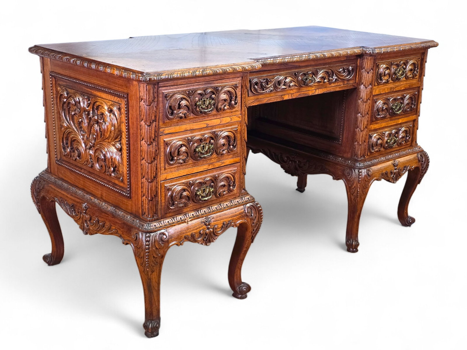 Italian Renaissance Style Carved Oak Kneehole Desk:  Carved oak kneehole desk with scrolling leaf relief decorations and carved molding. Shaped top with three drawers with pulls on each side and a central shallow drawer. On cabriole legs with car