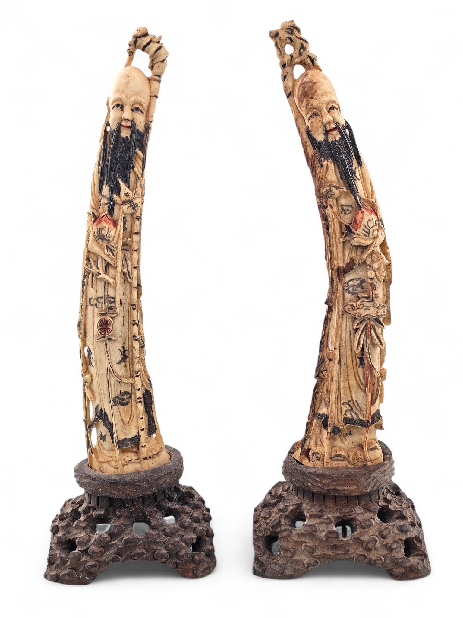 Pair of Oriental Chinese Bone Carving Figurines: Two carved Chinese figures with polychrome accents. Both are mounted atop intricately carved wooden bases. Wear consistent with age including surface wear, losses to paint. One figure has a notable cr