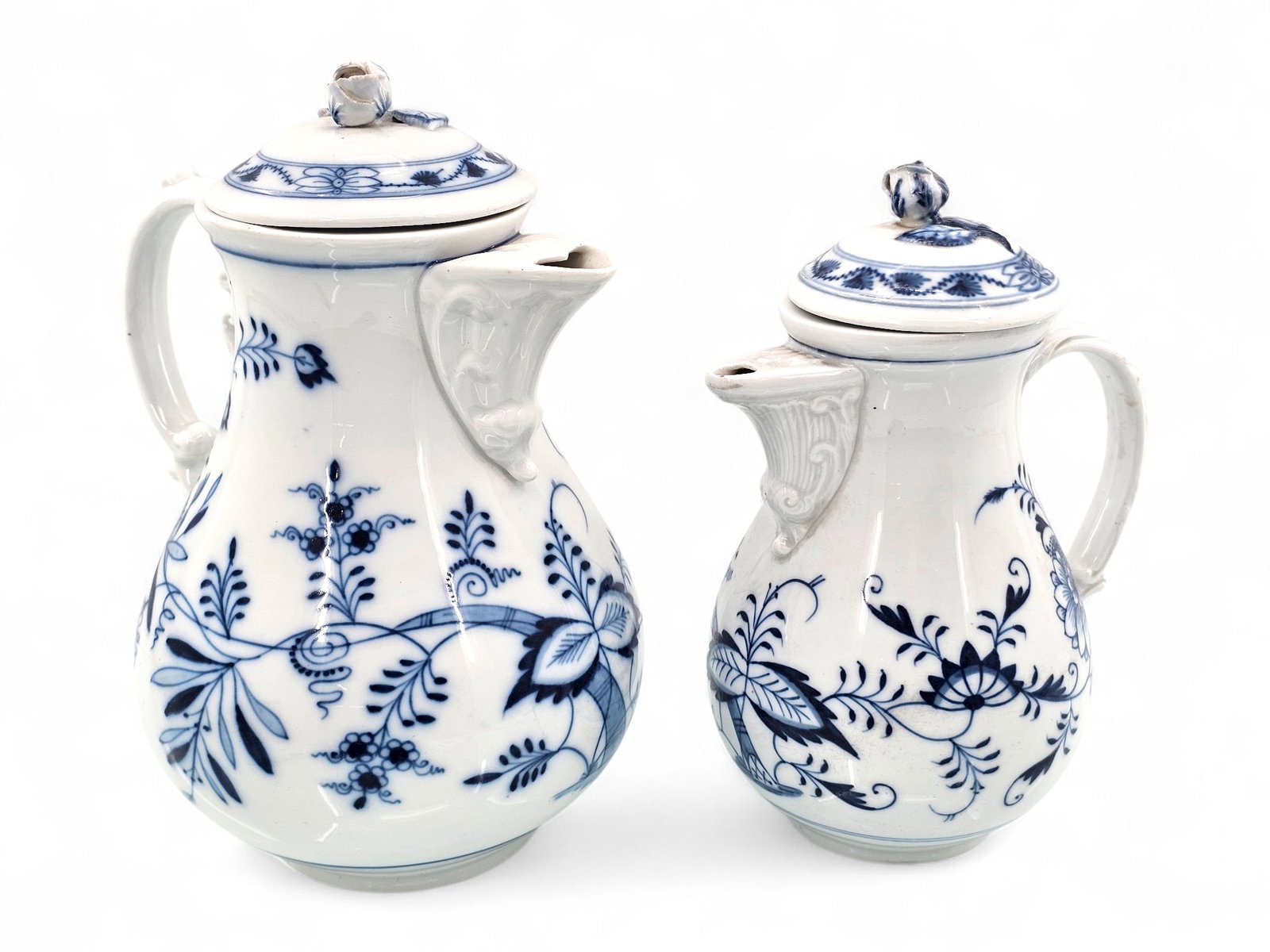 Two Meissen Blue Onion Porcelain Coffee Pots: Two Meissen porcelain coffee pots with Blue Onion design, featuring blue floral motifs. Both have lids adorned with a floral finial. The smaller coffee pot has a blue sword mark indicating c.1815 and