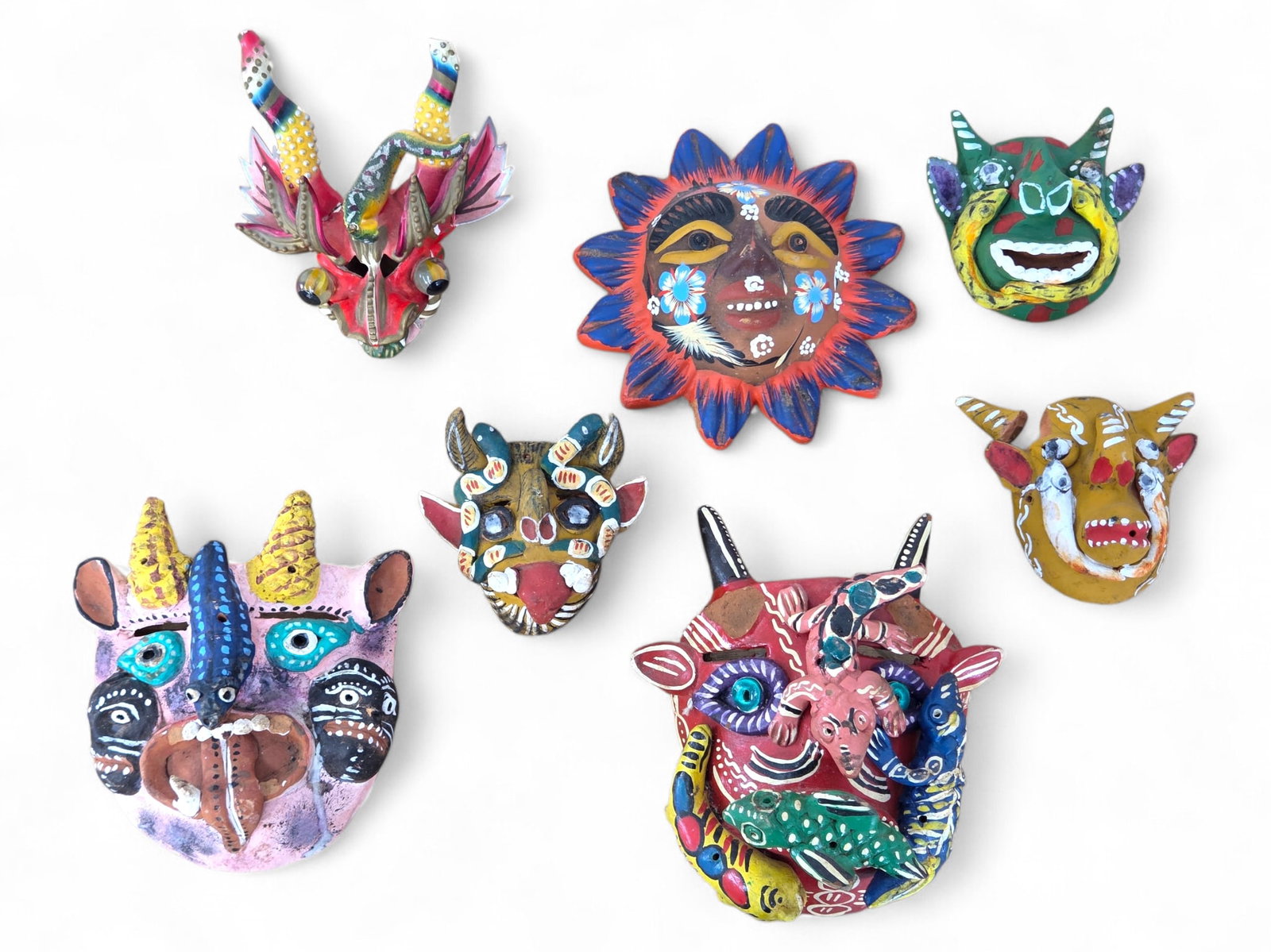 (7pc) Mexican Folk Art Pottery Decorative Masks: This lot includes 7 Mexican folk art terracotta and ceramic masks and wall hanging decorations, all hand painted. Some include horned devil figures, a sun shaped one, and more. Some with notable damag