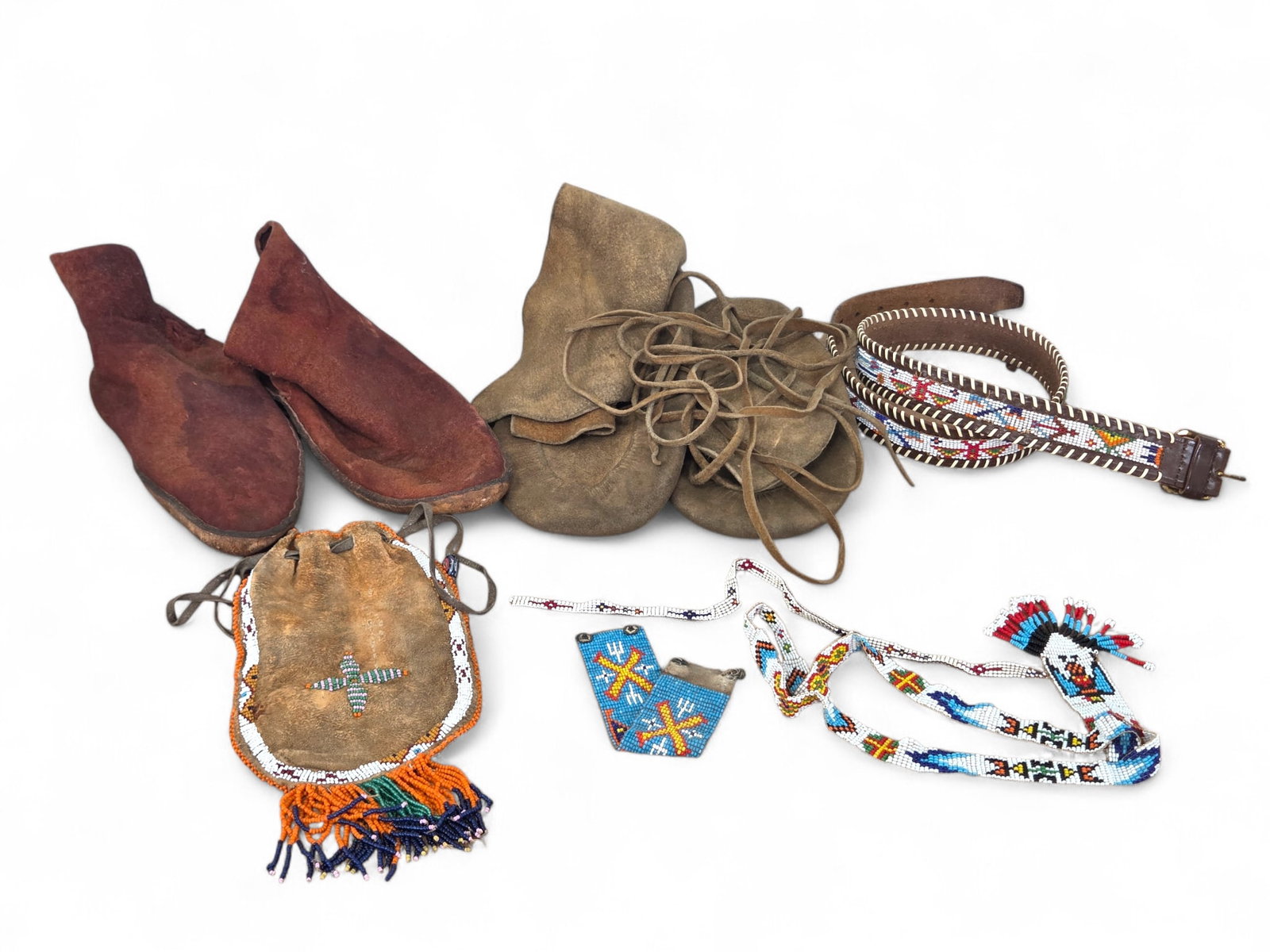Grouping of Native American Leather & Beadwork: Grouping of Native American handmade items including a beaded belt, two pairs of moccasins/shoes, a beaded leather pouch, and various other items. Wear consistent with age and use including some possi
