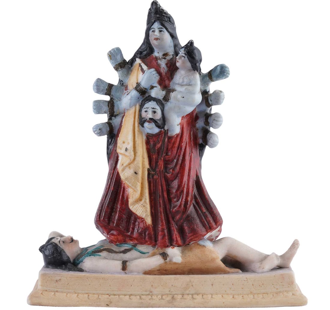 HAND PAINTED PORCELAIN SCULPTURE: KRISHNAKALI: Size: 13.9 x 14.8 cm (5.4 x 5.8 Inches) Goddess Kali is depicted with multiple arms fanned out behind her, wearing a deep red robe. She cradles a small child in her left arm while holding a severed