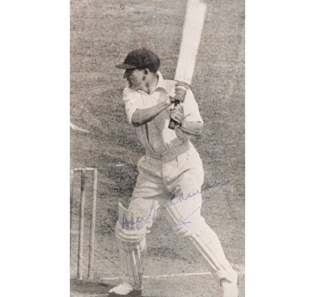 A SIGNED B/W PHOTOGRAPH OF SIR DONALD BRADMAN: Size: 17.3 x 11.3 cm (6.8 x 4.4 inches) Frame Size: 21.8 x 16.7 cm (8.5 x 6.5 inches) A signed photograph of Don Bradman, presented in a handmade frame crafted from teal green silk cloth. The frame