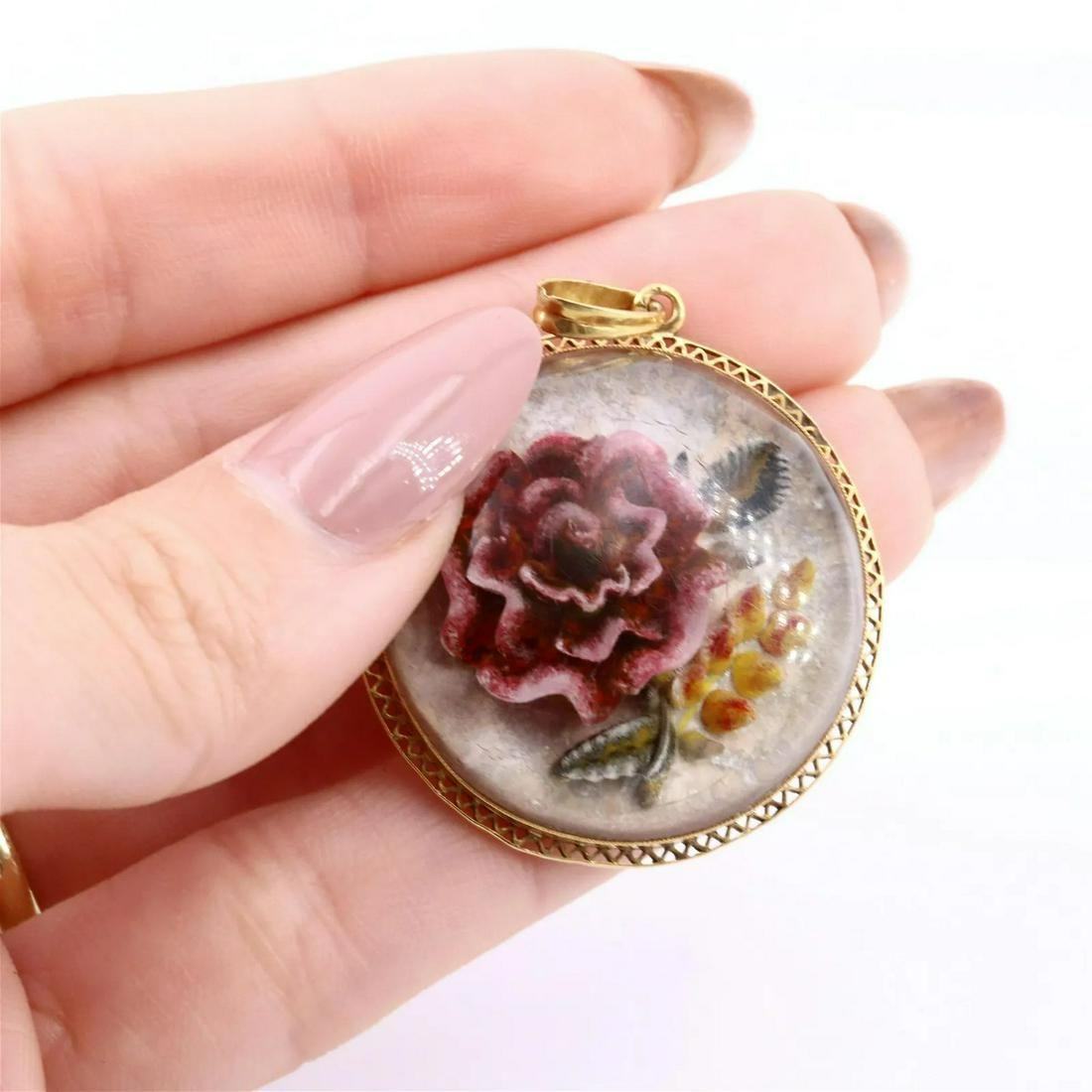 Vintage Intaglio 18k Gold Pendant: Circa 1910. Antique Intaglio Essex Crystal Pendant featuring a centerburgundy Rose. The back of the Pendant is crafted in 18k yellow Gold. Measurements: 1.4 Inches diameter. Weight: 7.6 grams.