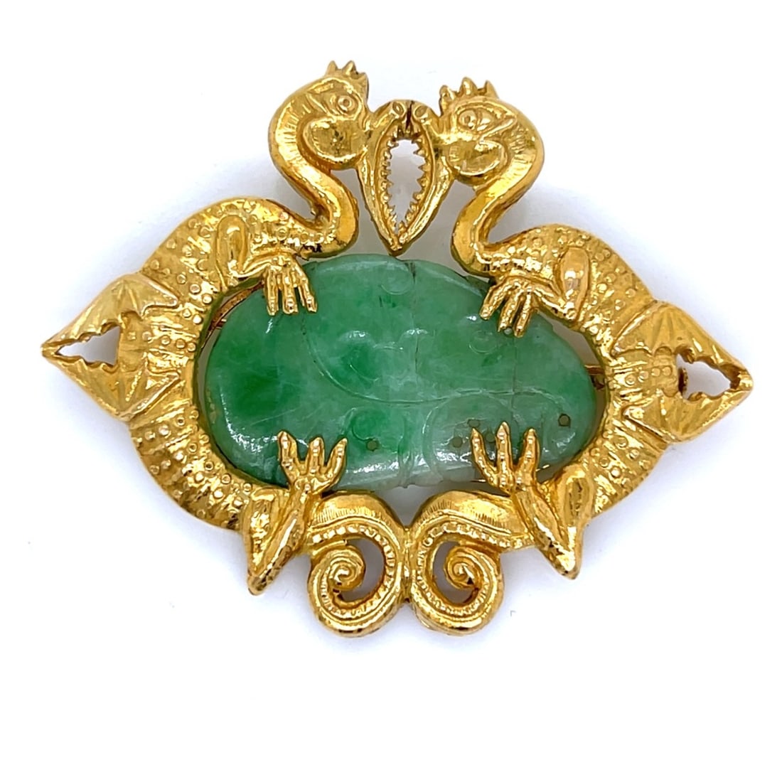 18K Yellow Gold Carved Jade Dragons Brooch/Pendant: 18K yellow gold brooch/pendant featuring a beautifully carved jade plaque framed by two sculptural dragons in rich, textured gold, with graceful openwork details and strong dimensional relief. A strik