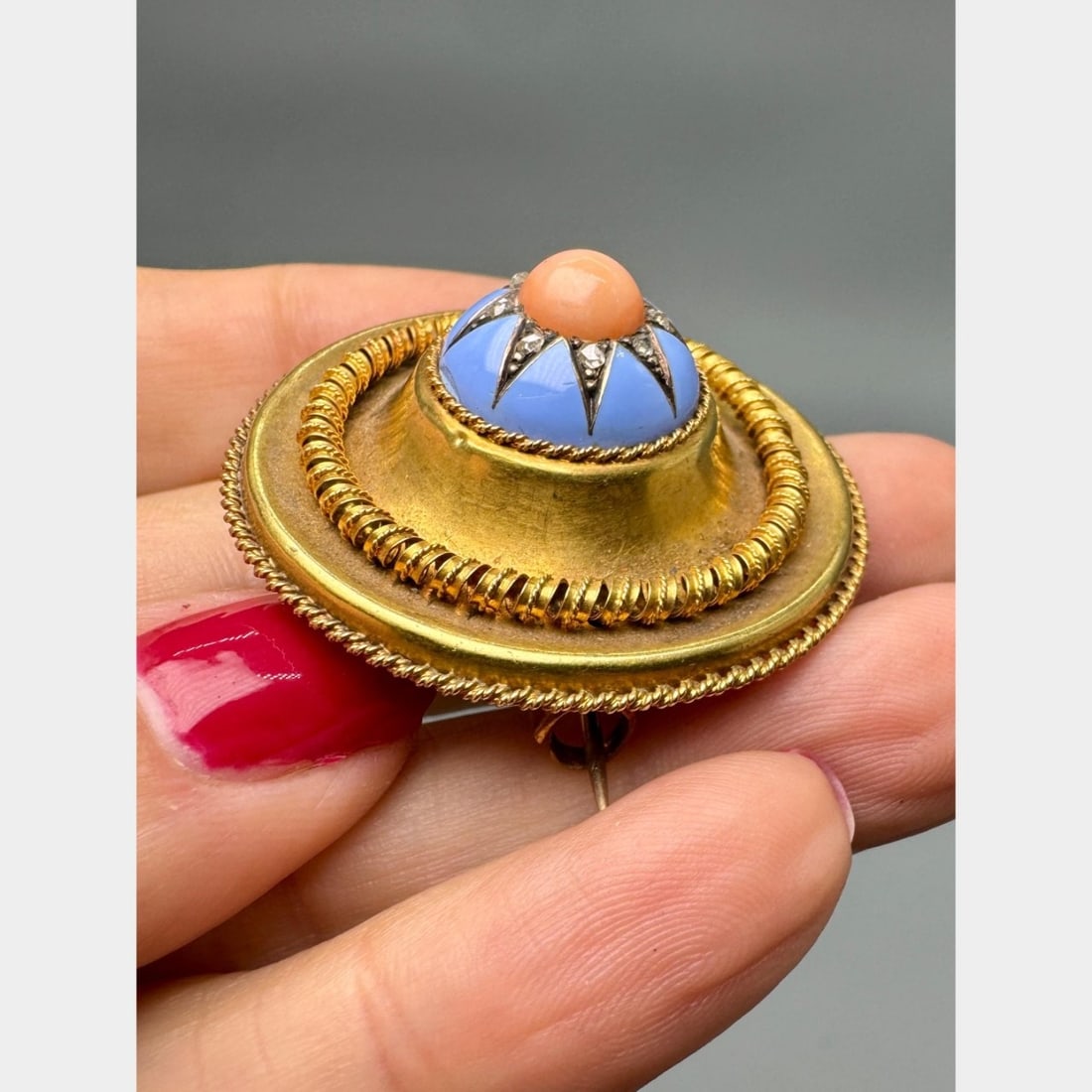Victorian 18K Yellow Gold Coral & Diamond Brooch: Victorian 18K yellow gold brooch featuring a warm coral cabochon set within a striking starburst motif, framed by a vivid blue enamel surround and accented with 8 rose-cut diamonds totaling approx. 0.