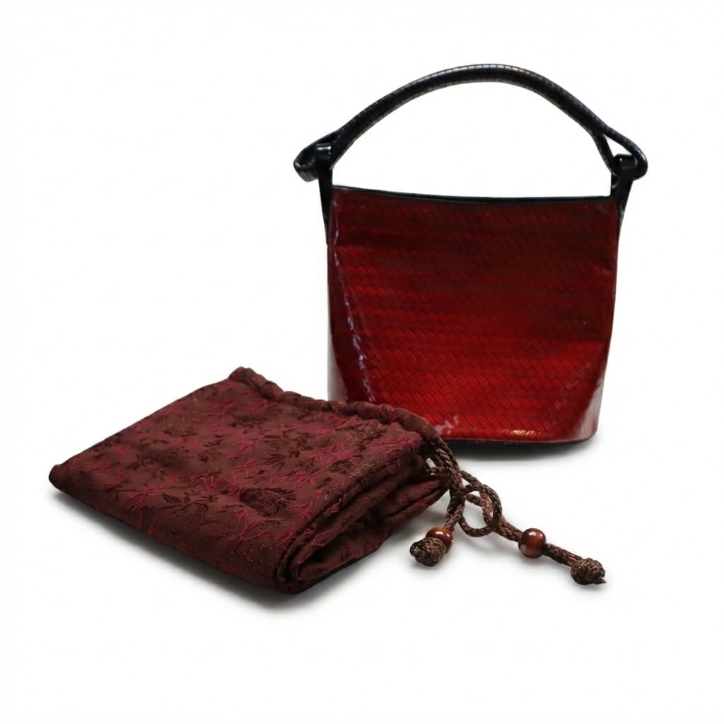 KENZO Vintage Red Lacquered Basket Bag: A truly exceptional vintage Kenzo piece—this rare hobo bag showcases the brand's signature red woven lacquered leather with striking black leather handles and embossed Kenzo hardware. Crafted in Fra
