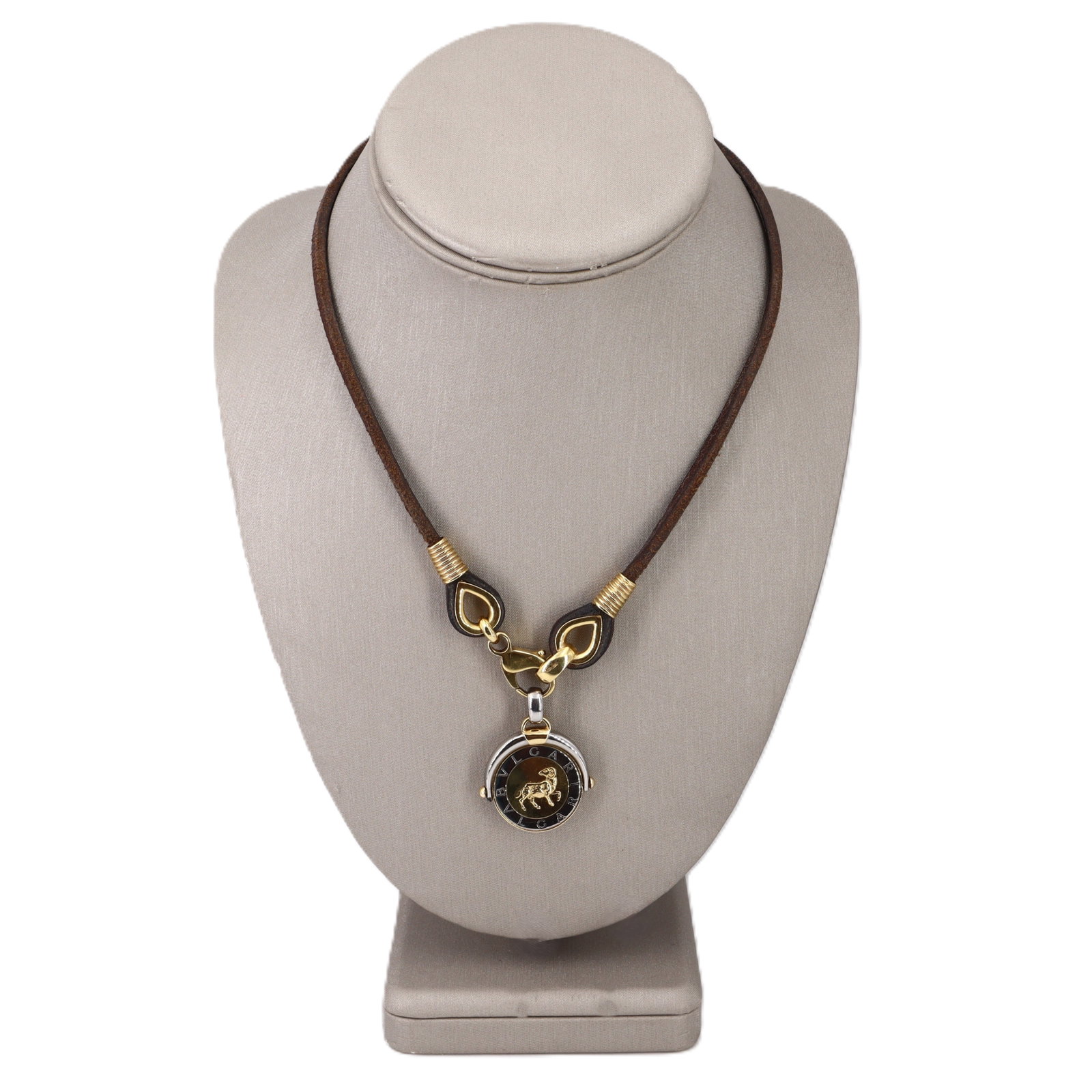 Bvlgari 18K Yellow Gold & Steel Capricorn Zodiac Flip Medallion Pendant Necklace: Iconic and collectible, this Bvlgari Capricorn Zodiac flip medallion pendant necklace pairs bold Italian design with luxe mixed materials: a 16-inch brown cord necklace with 18K yellow gold fittings, 
