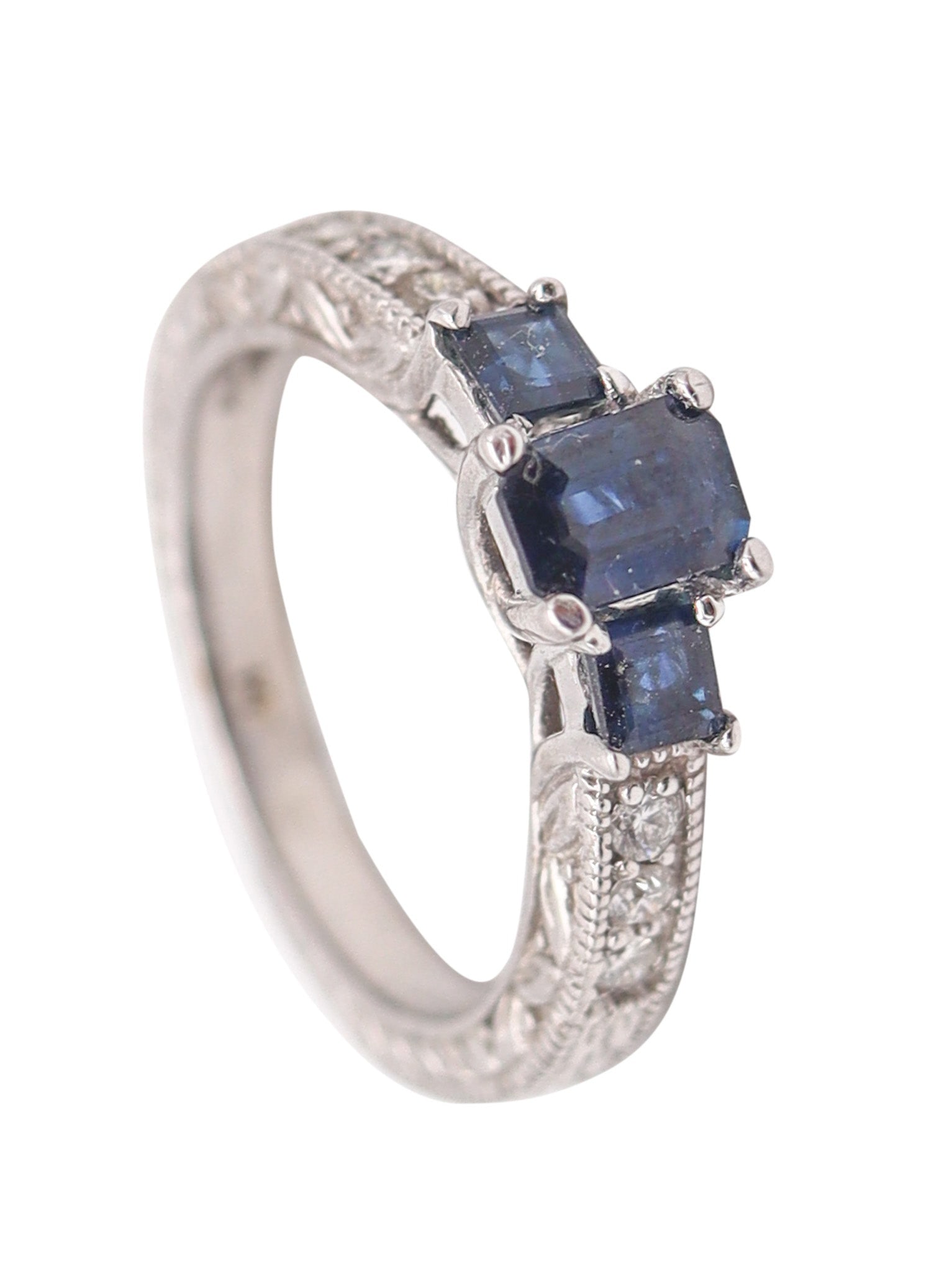 ART-DECO Revival Ring In 14Kt Yellow Gold With Blue Sapphires & VS Diamonds: Art Deco–revival ring crafted in solid 14K white gold with a high-polish finish, featuring floriated side detailing and a crisp, classic gemstone layout. Set with three prong-set vivid royal-blu