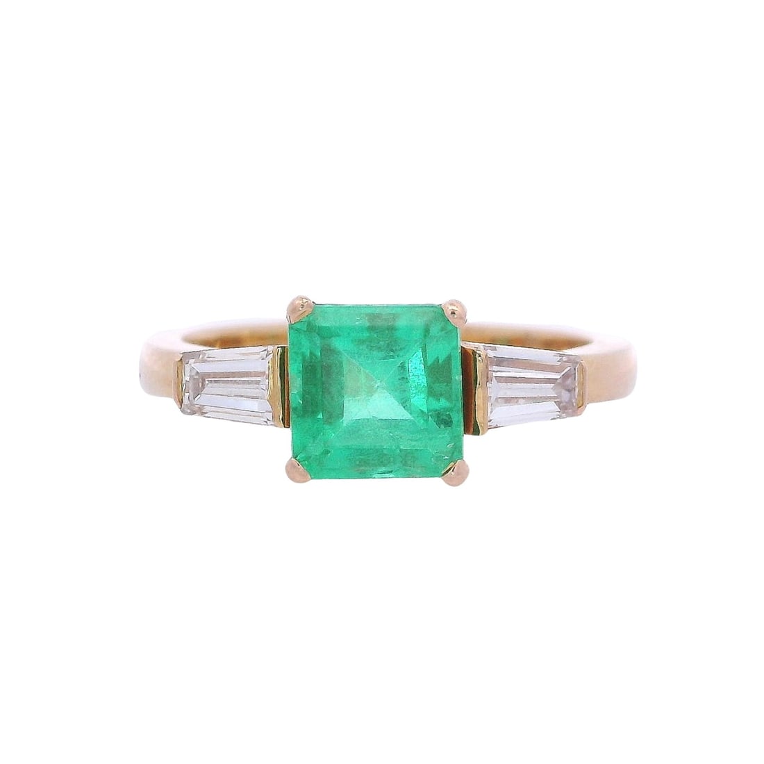 18kt yellow Gold Ring with Colombian Emerald & Diamonds: Three stones Ring crafted from 18kt yellow Gold, set with a center Emerald cut Colombian Emerald of Approx. 1.20 carats. Alon giwht two tapered Baguette Diamonds on the sides weighing together Approx.