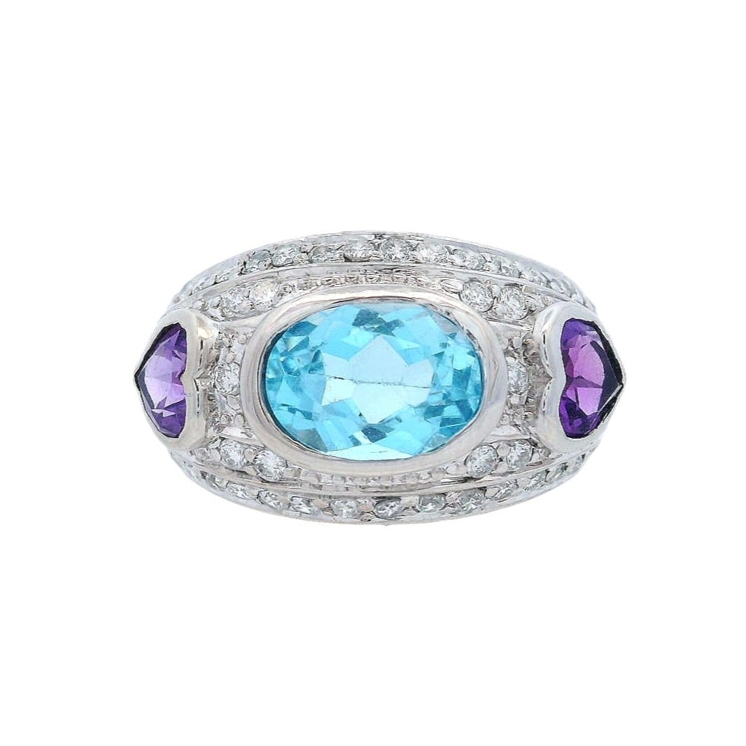 14K White Gold Ring with 4.00 CTW in Blue Topaz, Amethyst & Diamonds: 14K white gold cocktail ring centered with an oval-cut blue topaz approx. 2.50 ctw, flanked by two heart-shaped amethysts totaling approx. 1.00 ctw, and finished with pav?-set round diamonds totaling 