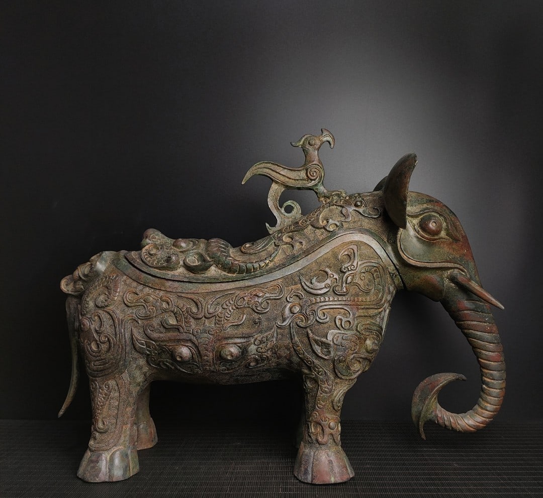 Shang and Zhou bronze elephant trunk wine vessel: A rare bronze incense burner with gilt inlay, from a distinguished collection. Exquisitely crafted and beautifully designed, it weighs 3300g and measures 79cm in height and 17cm in width. Provenance:f