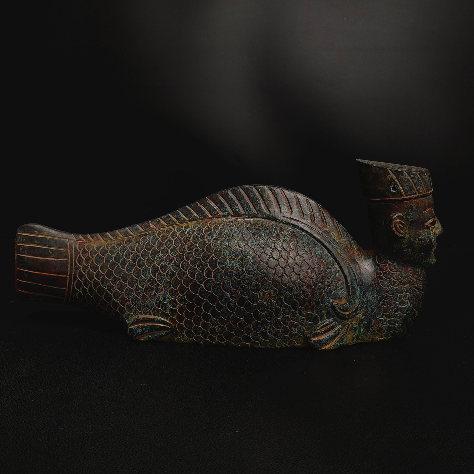 Bronze mermaid-shaped artifact from the old collection: This bronze fish-shaped zun (wine vessel) from the collection is modeled after a fish, with smooth and vivid lines. The body is covered with fine fish scale patterns, and the fins and tail are realist