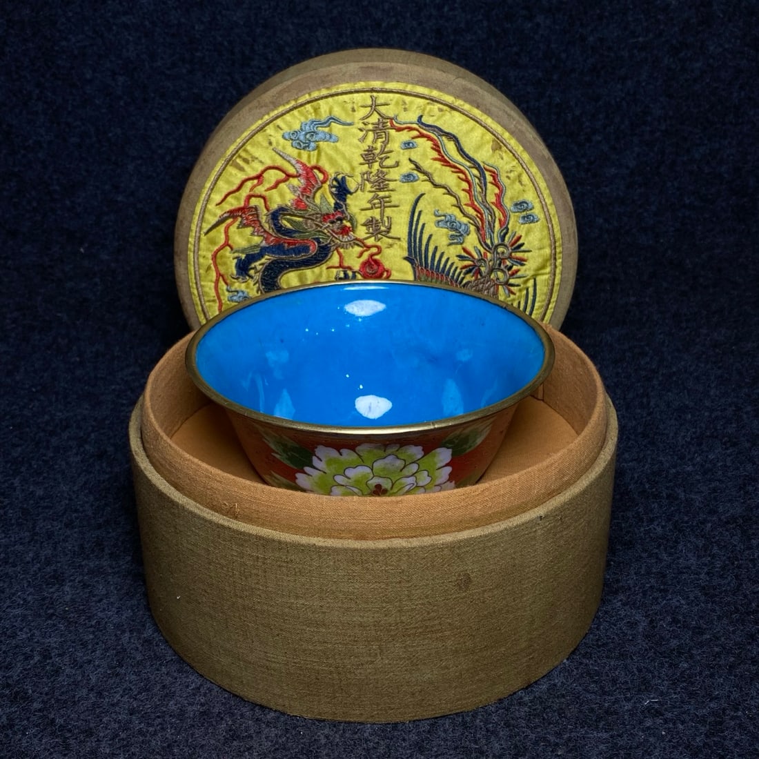 A precious cloisonne enamel bowl with a copper body, made in the embroidery collection box from the: The embroidered box, made during the Qianlong reign of the Qing Dynasty, contains a cloisonne enamel bowl with a copper body. The bowl's dimensions are: diameter 15.5 cm, height 7.3 cm. The embroidere