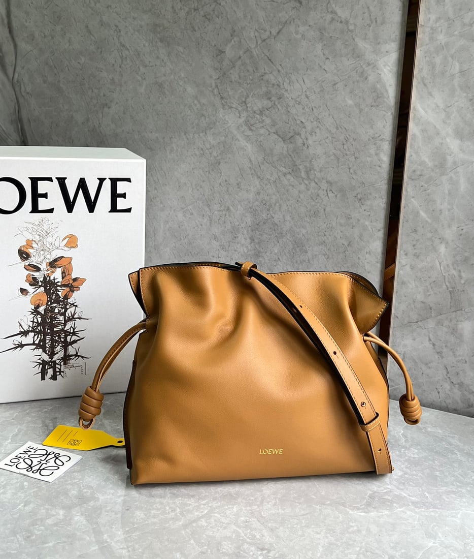 LOEWE Flamenco: The LOEWE Flamenco lucky bag is crafted from premium, supple calfskin with a drawstring closure, featuring a gold suede lining and a widened shoulder strap for carrying it over the shoulder, crossbody