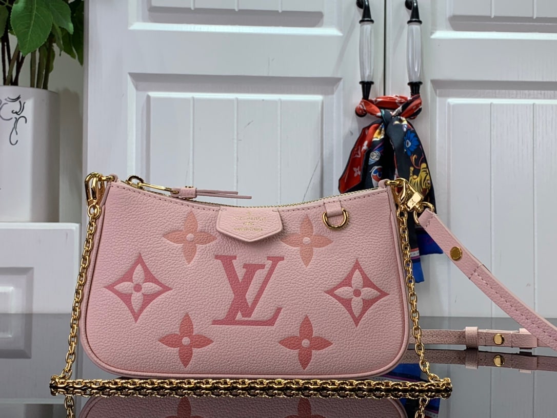 LV Easy Pouch handbag: The Easy Pouch handbag, from the LV Gradient collection, is crafted from Monogram Empreinte embossed leather in a vibrant summer sunset hue. Ample space accommodates everyday essentials, while a detac