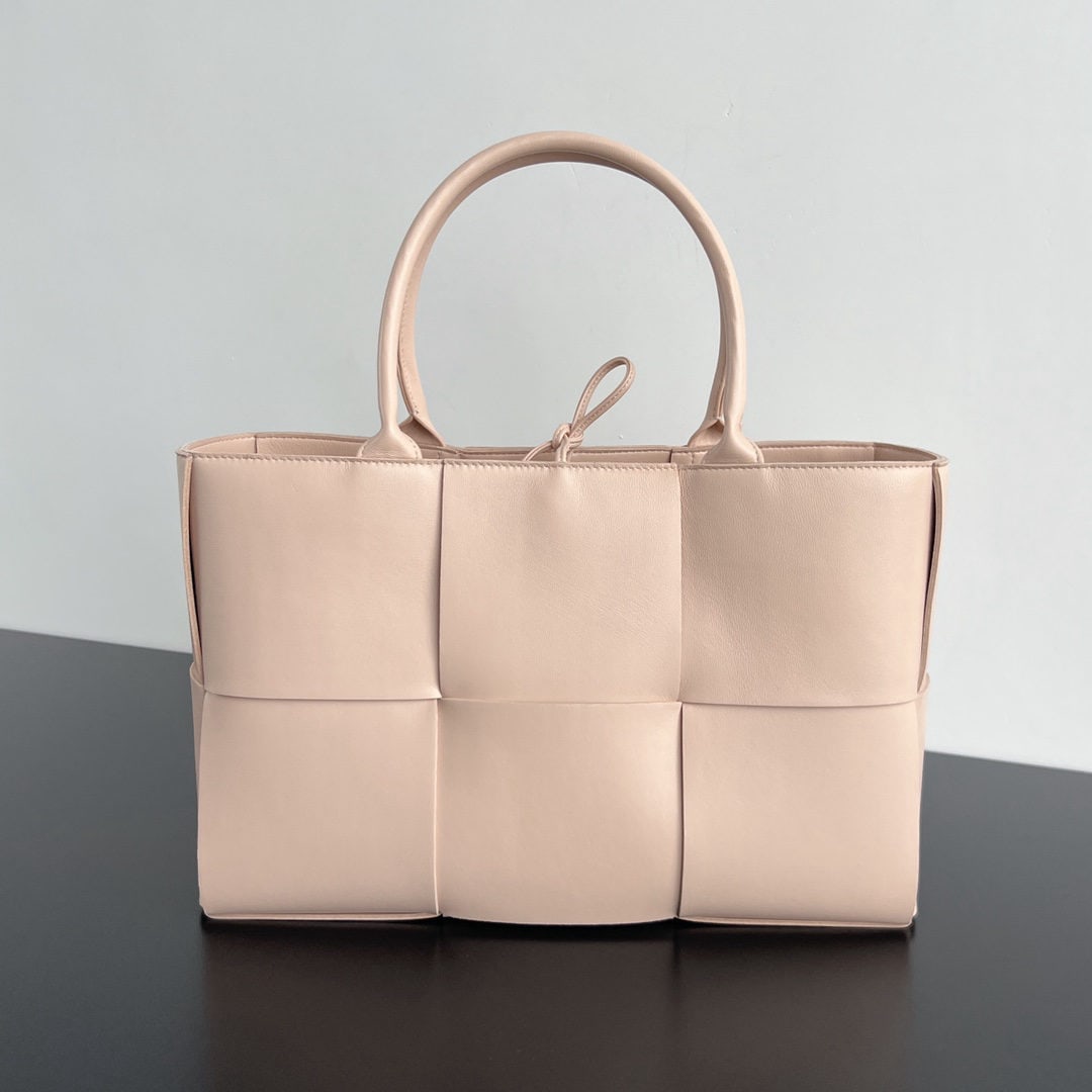 Bottega Veneta: The Bottega Veneta ARCO TOTE grained woven leather tote bag is a sophisticated 3 compartment design. The large woven element makes it a perfect commuter bag, with a high gloss finish. The overall