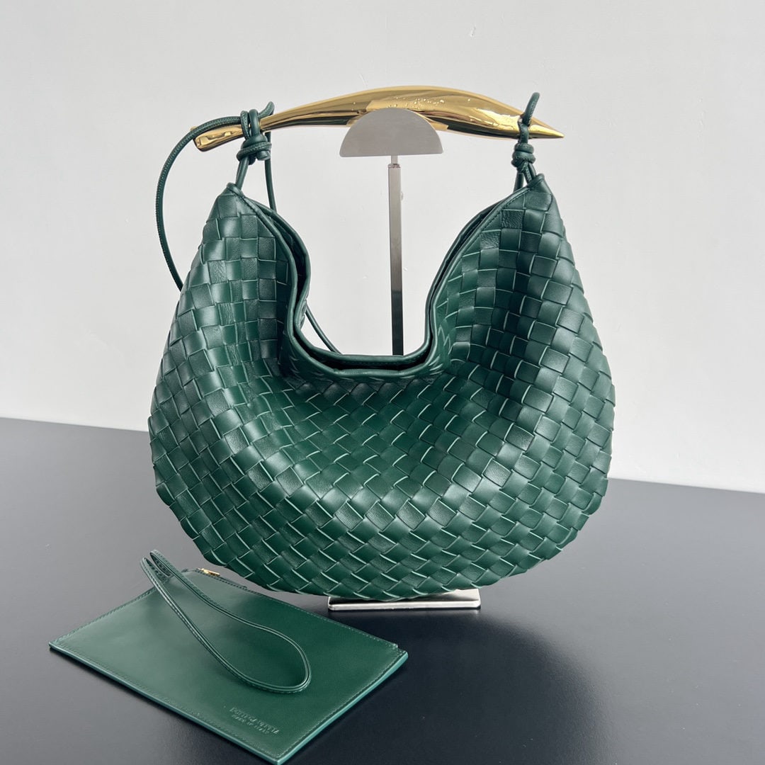 Bottega Veneta: The Bottega Veneta Sardine is a size larger than the original, featuring an additional shoulder strap for greater comfort and hands free carrying. The metal handles and classic woven design combine to