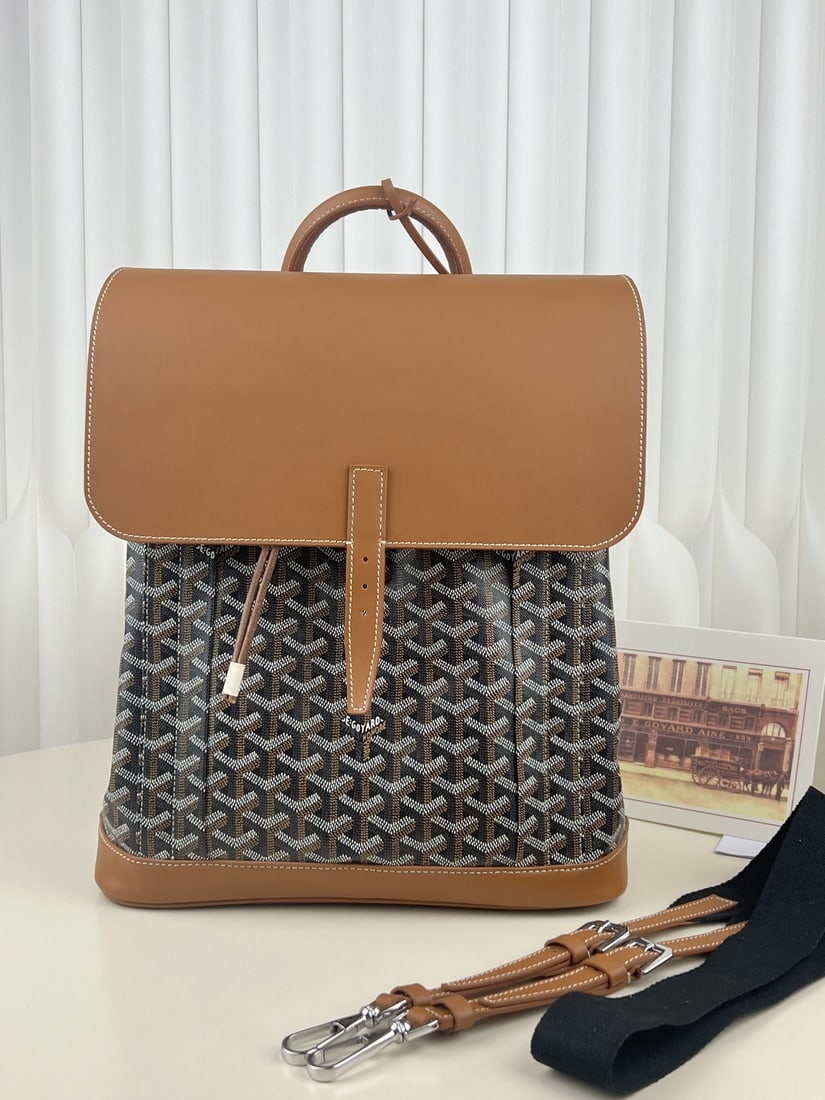 Goyard Alpin MM: The Goyard Alpin MM men's flap backpack is a design by Goyard specifically for urban adventurers. A reinvention of the brand's renowned Steamer bag, it was a loyal companion to 20th century travelers.