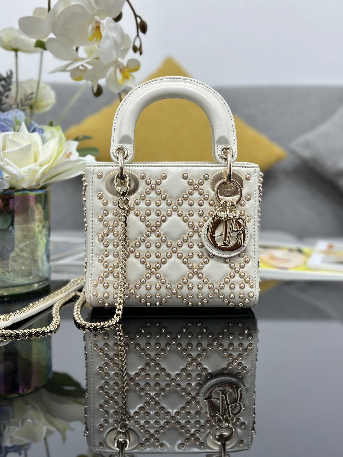 Christian Dior: The Lady Dior features a three panel pearl studded white design, lined with lambskin, crafted from waxed calfskin and adorned with classic cannage beads for a unique and sophisticated look. A light go