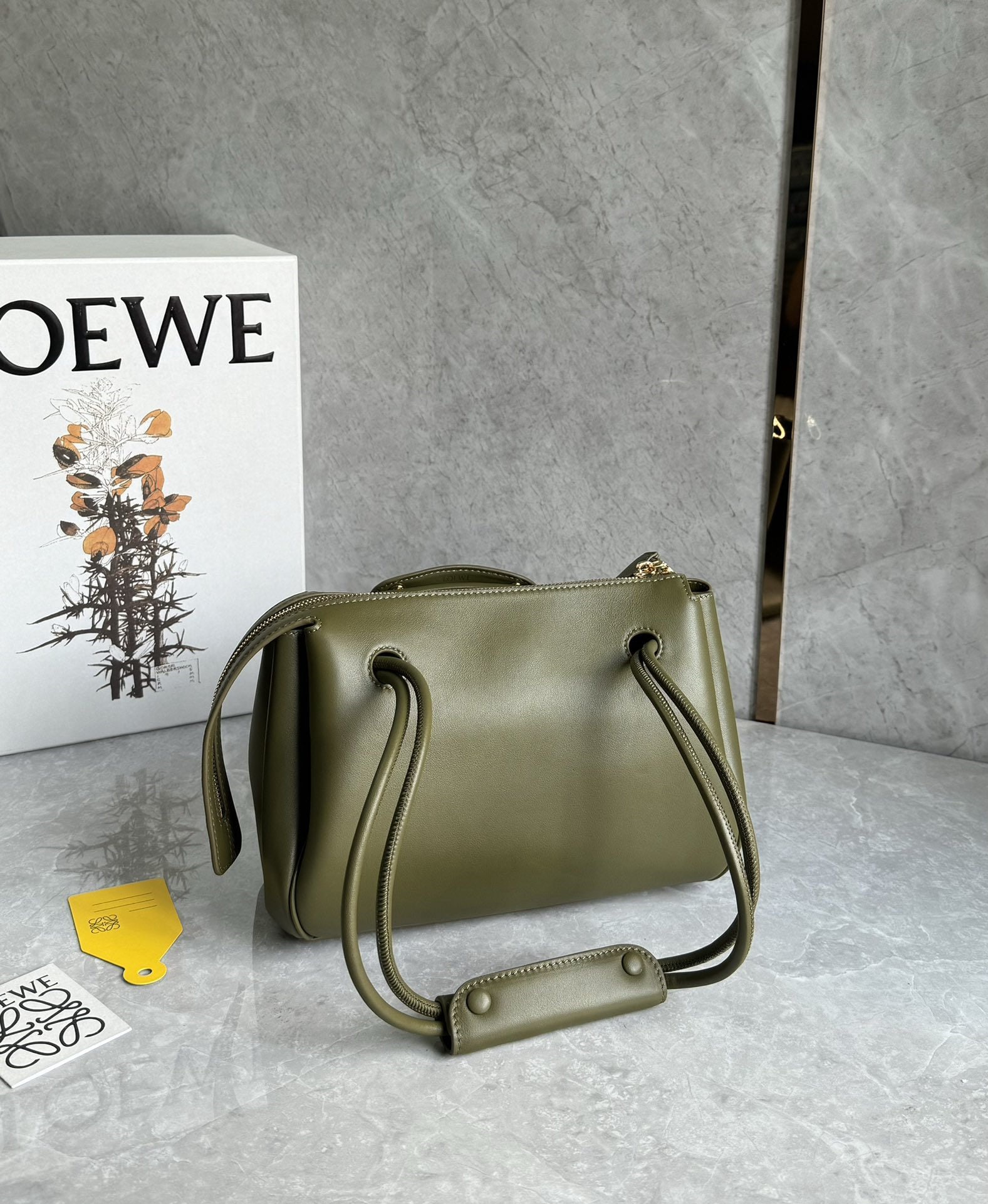 LOEWE: The LOEWE Small Madrid bag features a soft, structured trapezoidal shape with a gusseted design, adjustable handles, and a Pebble magnetic closure. It's crafted from supple cowhide leather, with a