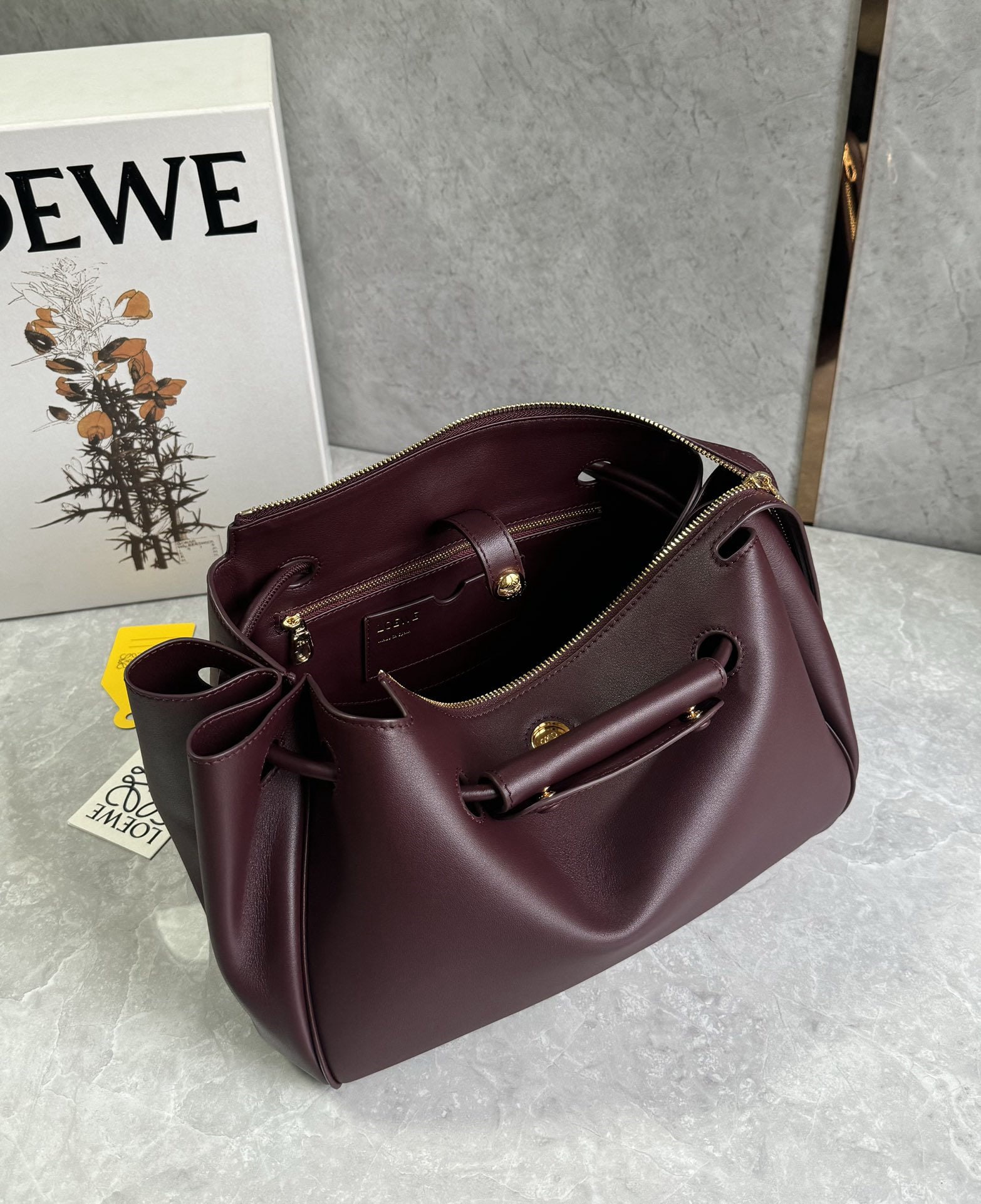 LOEWE: The LOEWE Madrid bag features a soft, structured trapezoidal shape with a gusseted design, adjustable handles, and a Pebble magnetic closure. It's crafted from supple cowhide leather, with a premium