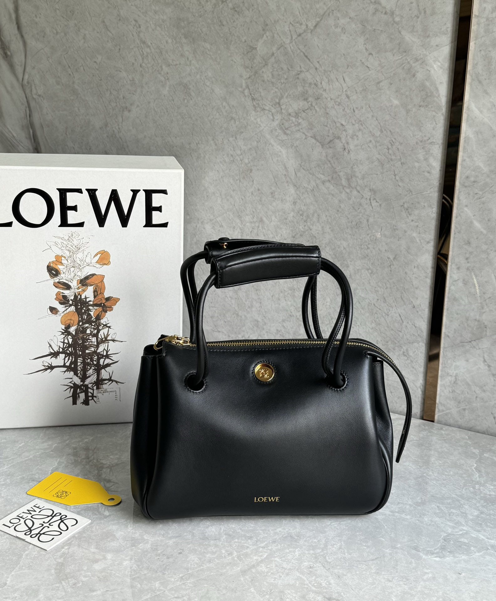 LOEWE: The LOEWE Small Madrid bag features a soft, structured trapezoidal shape with a gusseted design, adjustable handles, and a Pebble magnetic closure. It's crafted from supple cowhide leather, with a pre