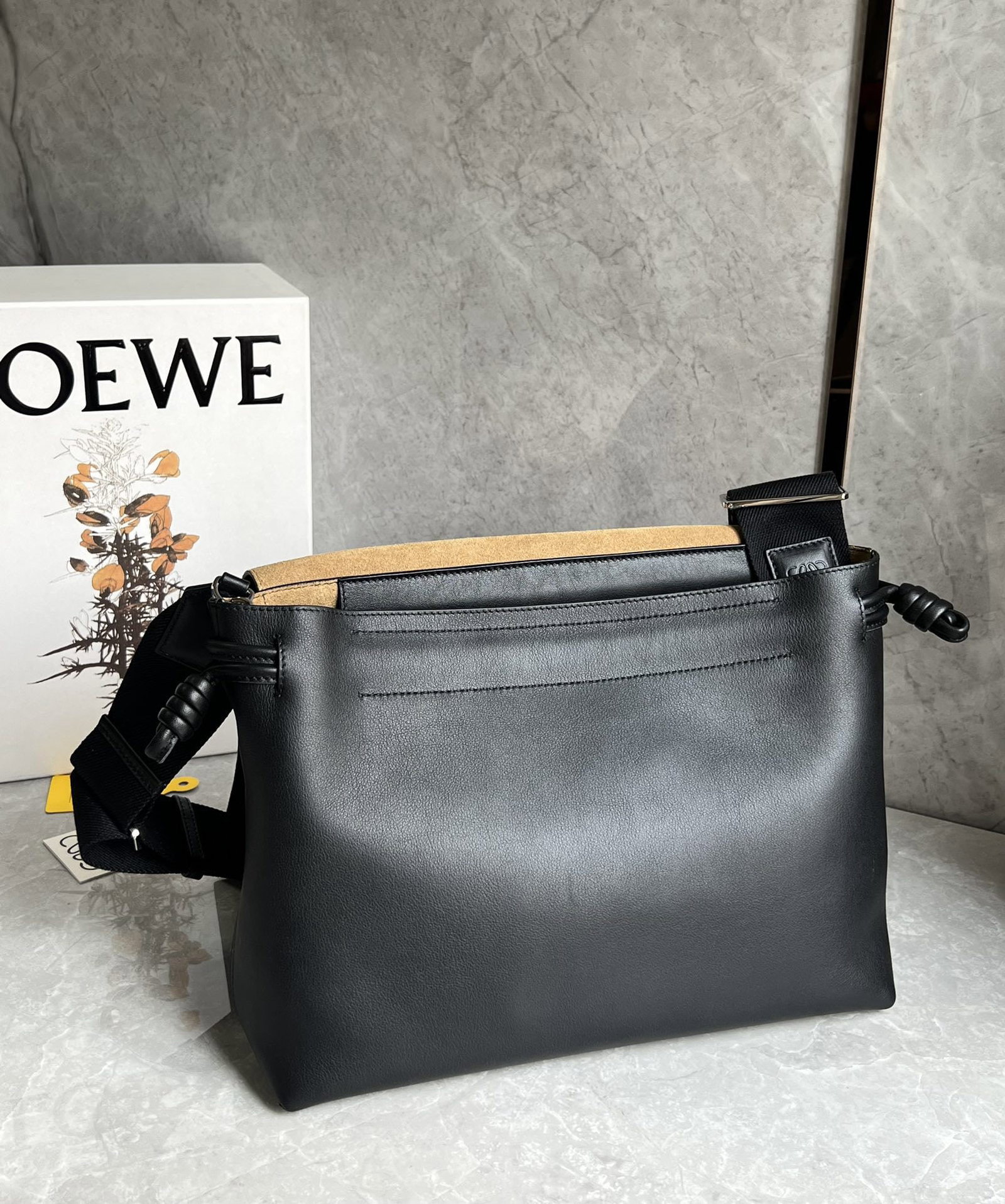 LOEWE: This LOEWE Flamenco satchel messenger bag is crafted from supple calfskin in glossy finish. It reimagines the classic Flamenco bag as a practical crossbody bag with a drawstring closure and the