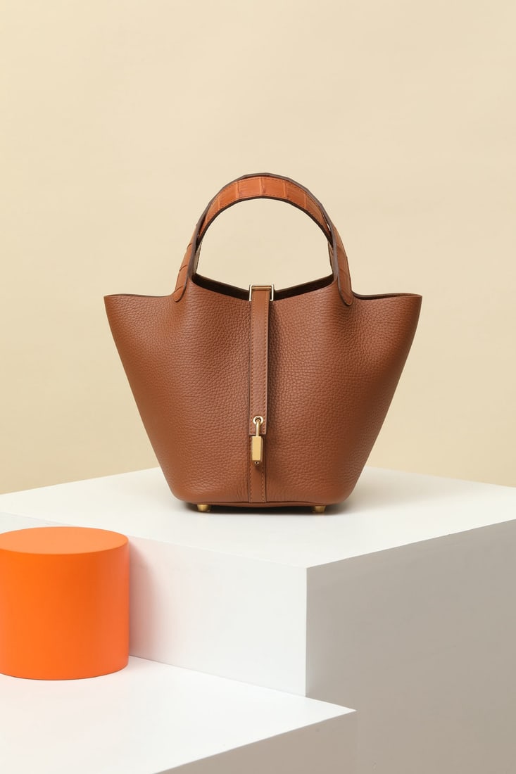 Hermes: Model: CL18 Code: CL180340 Color: CK37 Golden Brown Dimensions: 18cm (L) x 13cm (D) x 18cm (W) Material: TC/Matte Alligator (Square Opening) The Picotin 18 Touch bucket bag features an added strap at 