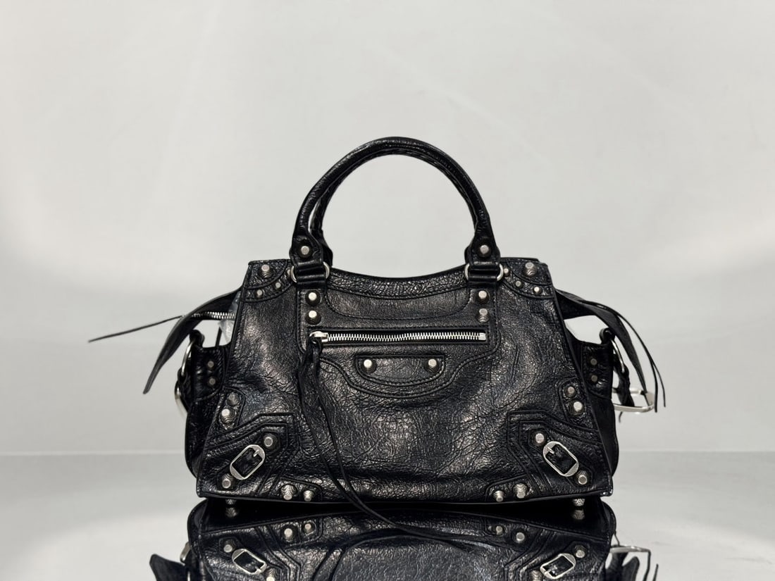 Balenciaga motorcycle bag: The Balenciaga Neo Cagole motorcycle bag combines the classic Neo Classic Le Cagole design with Italian crackled lambskin. It retains the classic motorcycle bag elements such as rivets and tassels, wh