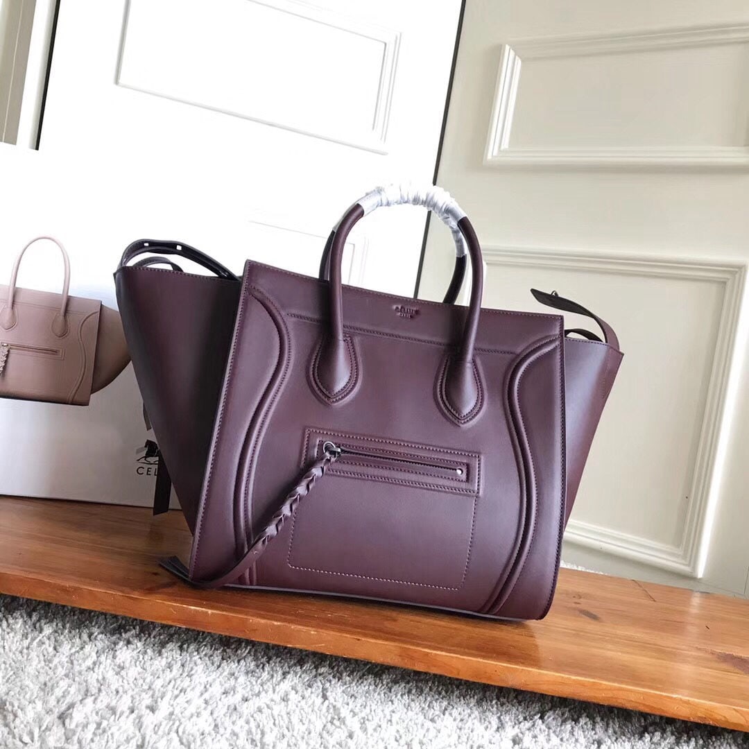 Celine: Celine XPhantom burgundy plain weave Phantom Batwing bag features a clasp on the side leather strap for closure. It has a small zip pocket on the front and an interior zip pocket. Rivets at the bottom
