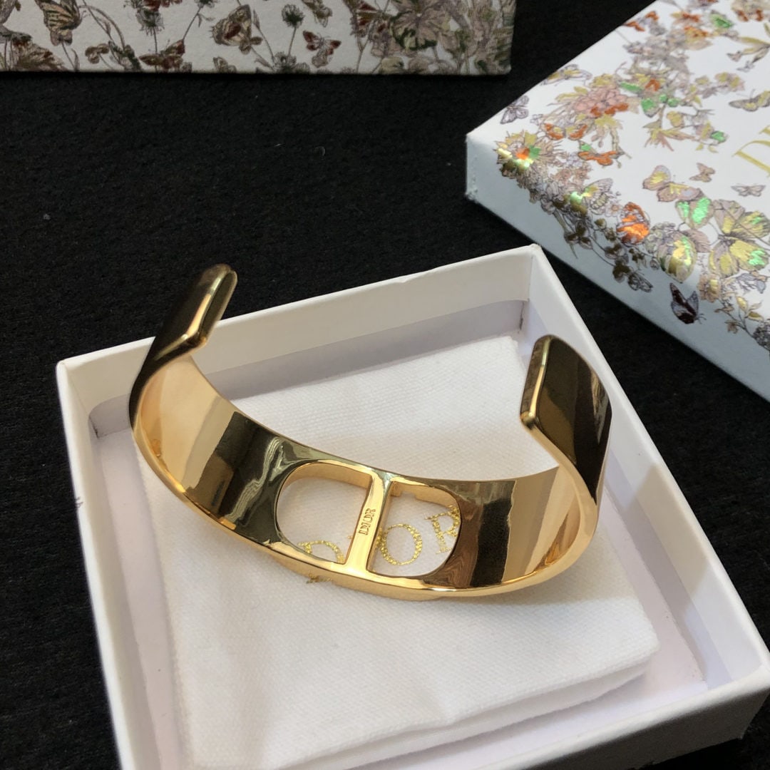 "CD" Open Bracelet: This "CD" open bangle is one of the iconic pieces in the Montaigne collection, which includes many classic and versatile styles. This minimalist open bangle features a striking gold plated white metal