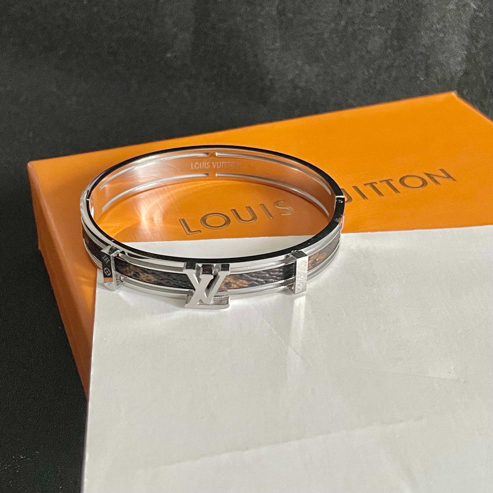 LV monogrammed engraved four leaf clover unisex gold leather bracelet: This unisex gold leather bracelet features an engraved four leaf clover design by Louis Vuitton. Its unique blend of retro and avant garde style has made it a favorite among women since its release. E