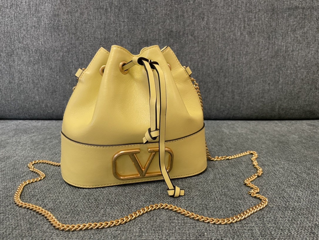 Valentino: Valentino Mini Bucket Bag Valentino Mini Lambskin Bucket Bag Vintage Brass Antique Finish Logo and Hardware Drawstring Closure Chain Shoulder Strap Dimensions: 20cm (W) x 17cm (H) x 8cm (D) We offer F