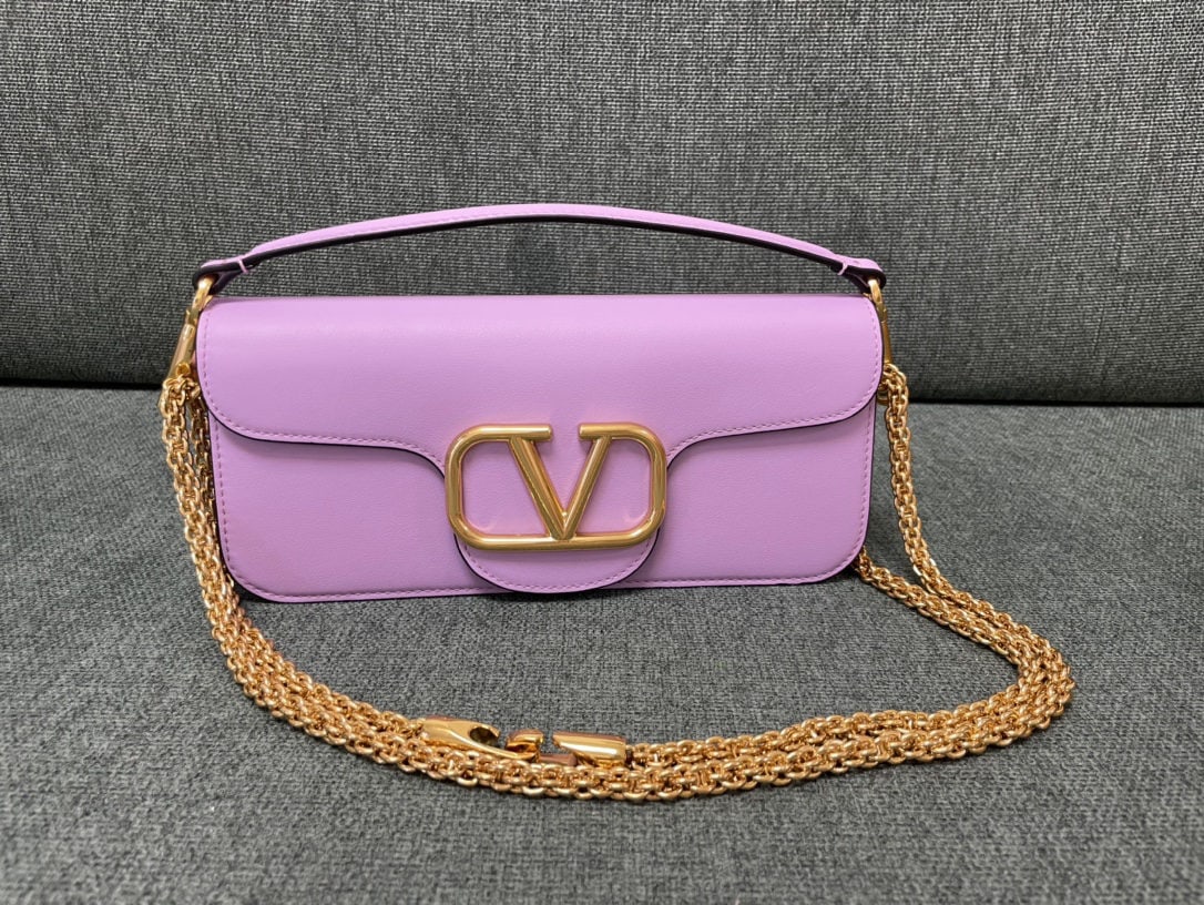 Valentino: Taro purple Valentino calfskin handbag with metal V logo Signacar trim features detachable handles and a detachable sliding chain for shoulder, crossbody, or hand carry. Vintage brass distressed finis