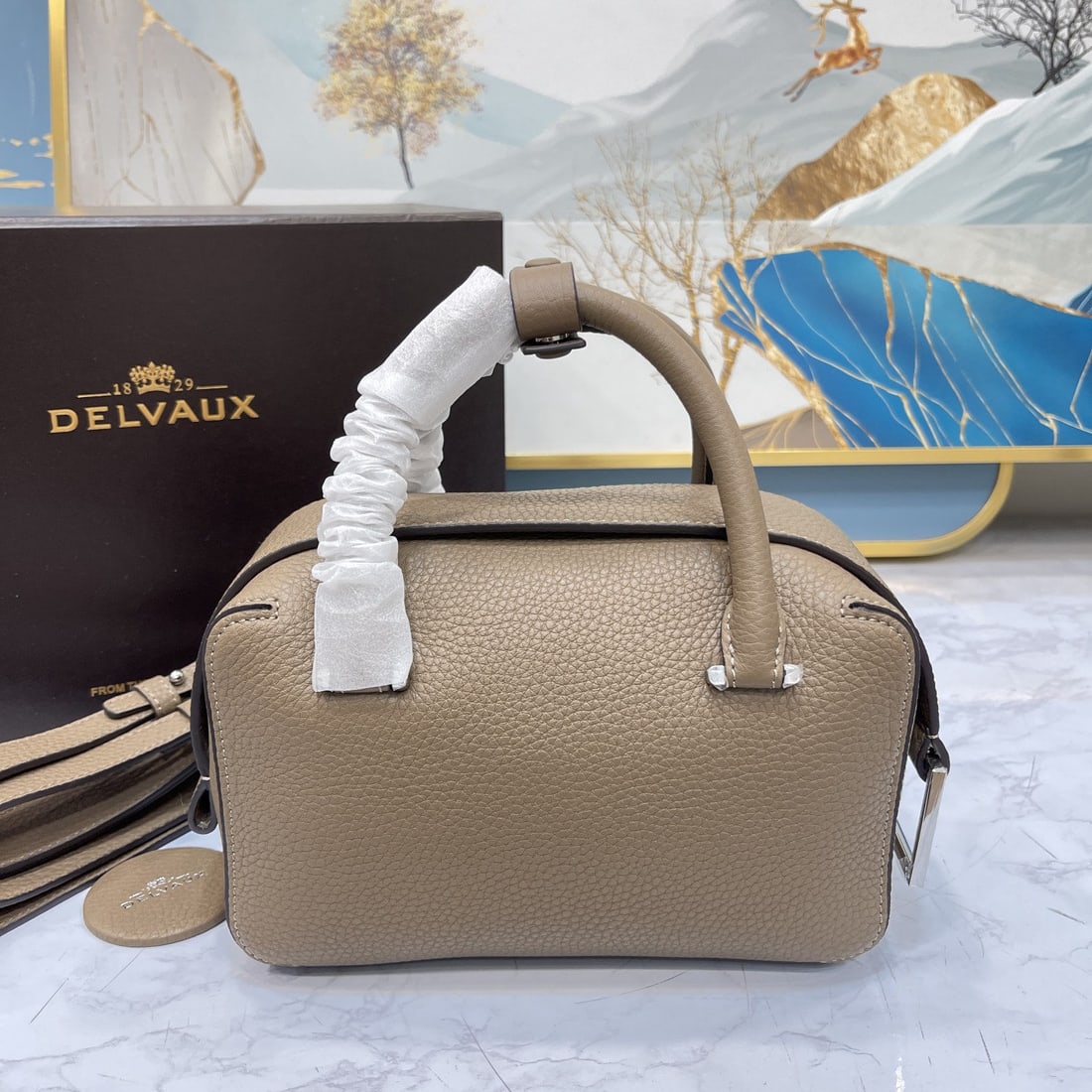 Delvaux: The small, elephant gray Cool Box bag is youthful and modern, a trendsetter. Its casual, lightweight, and comfortable design embodies a unique spirit, combining beauty and practicality. The Cool Box M