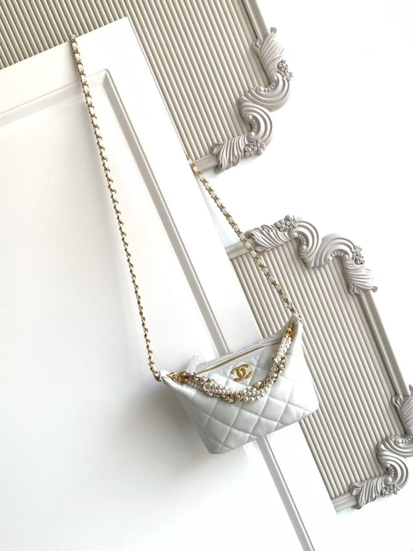 CHANEL Pearl Chain Lunch Box Bag: This pearl chain lunchbox bag features a classic quilted pattern, made of lambskin with a vintage metal chain adorned with pearls. The hobo shape offers moderate capacity, easily holding a phone and l