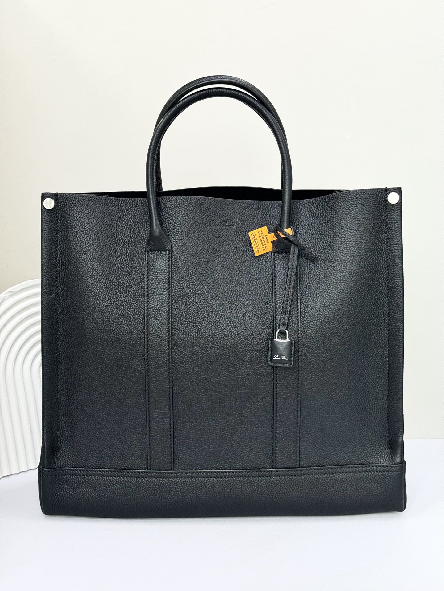 Loro Piana Beam Small Tote Bag: The Loro Piana Beam Small Tote Bag in black pays homage to Loro Piana's rich textile tradition by being named after the "beam," a crucial component of the loom. Its retractable base, inspired by the