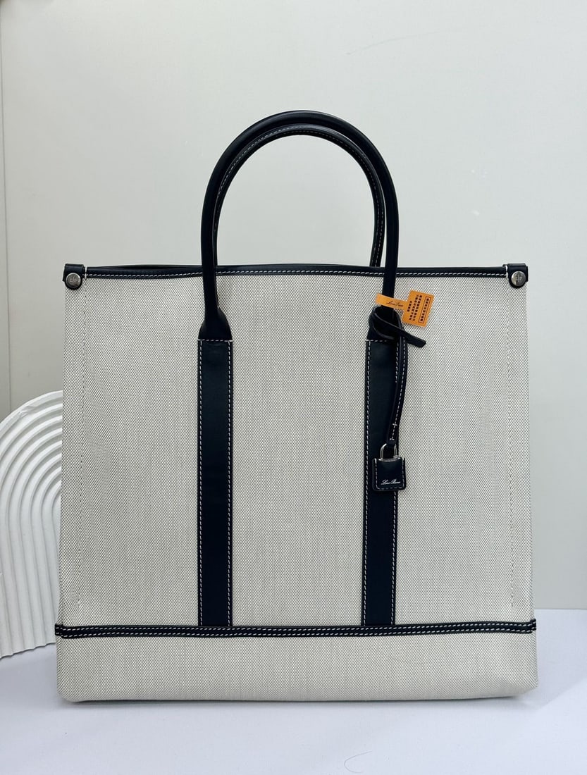 Loro Piana Beam Small Tote Bag: This Loro Piana Beam Small Tote Bag in blue canvas and leather pays homage to Loro Piana's rich textile tradition. Named after the "beam," a crucial component of the loom, its retractable base is insp