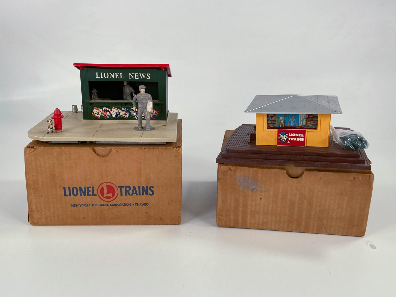 Lionel Postwar #118 Newsstand with Whistle and #128: Lionel Postwar #118 Newsstand with Whistle and #128 Animated Newsstand, with both items in C7 and both having boxes.