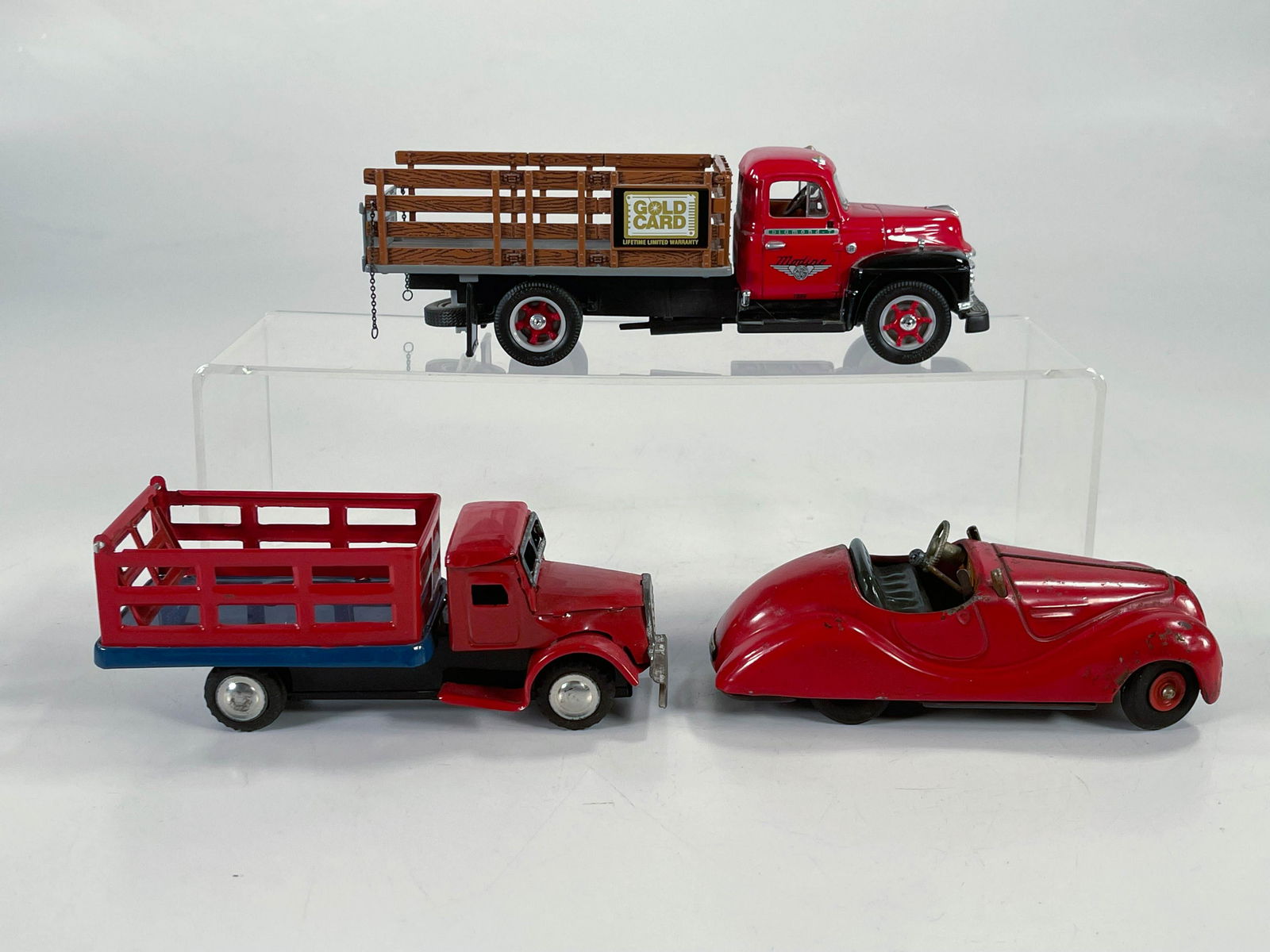 Toy stake truck x2 and Schuco Examinco #4001 race car: Toy stake truck x2 and Schuco Examinco #4001 race car, the stake trucks x2 in C7 plus and the Schuco automobile car is in C6 given the dent on the rear hatch [do not know if it runs].