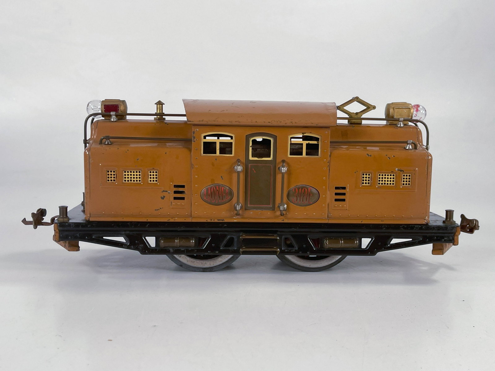Lionel Prewar #318E tan electric locomotive: Lionel Prewar #318E tan electric locomotive, in C5 plus to C6 minus condition with a noticeable repaint line because of the dent [view pictures closely].